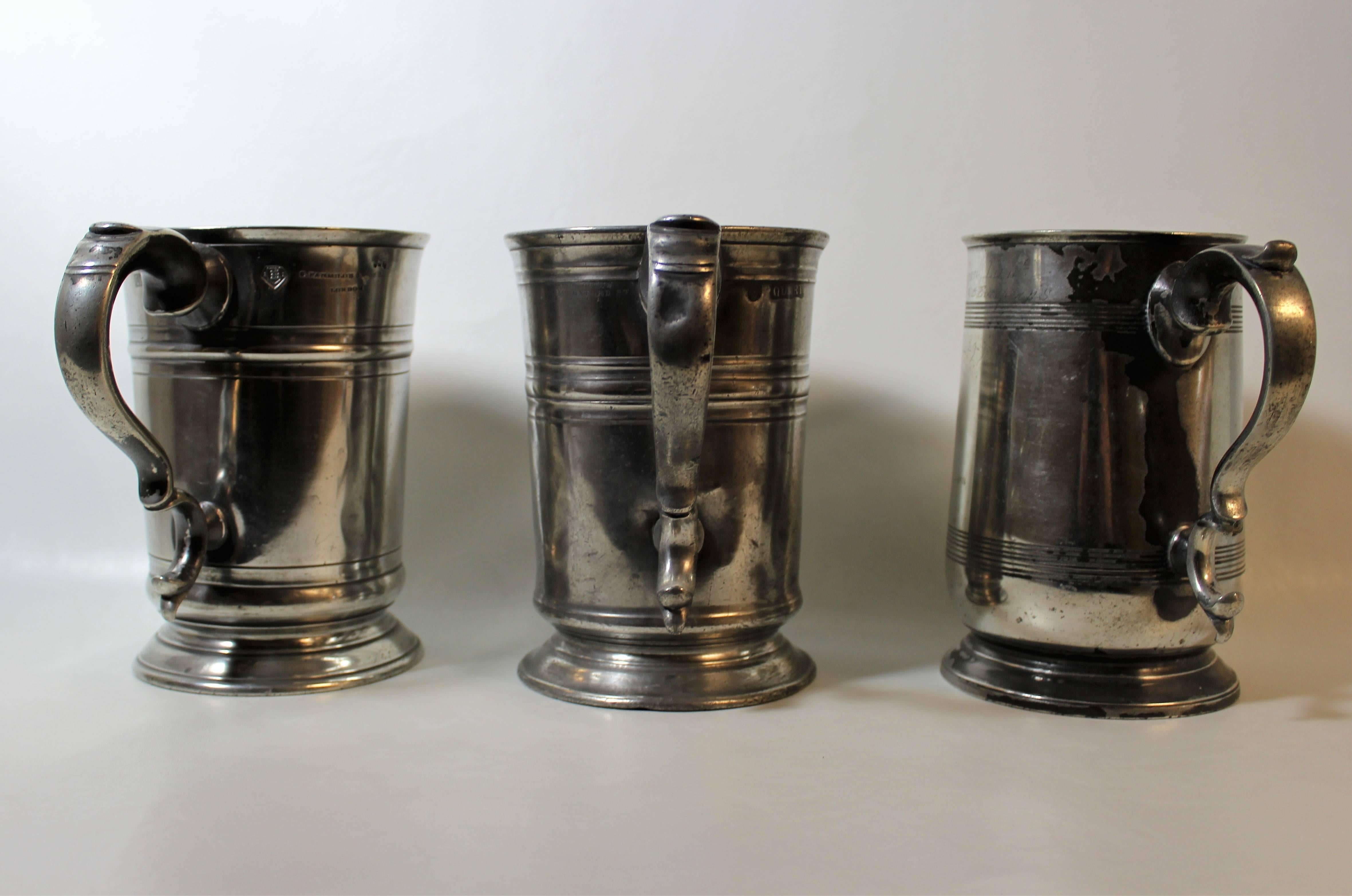 Three English pewter tankards with various engravings and marks.