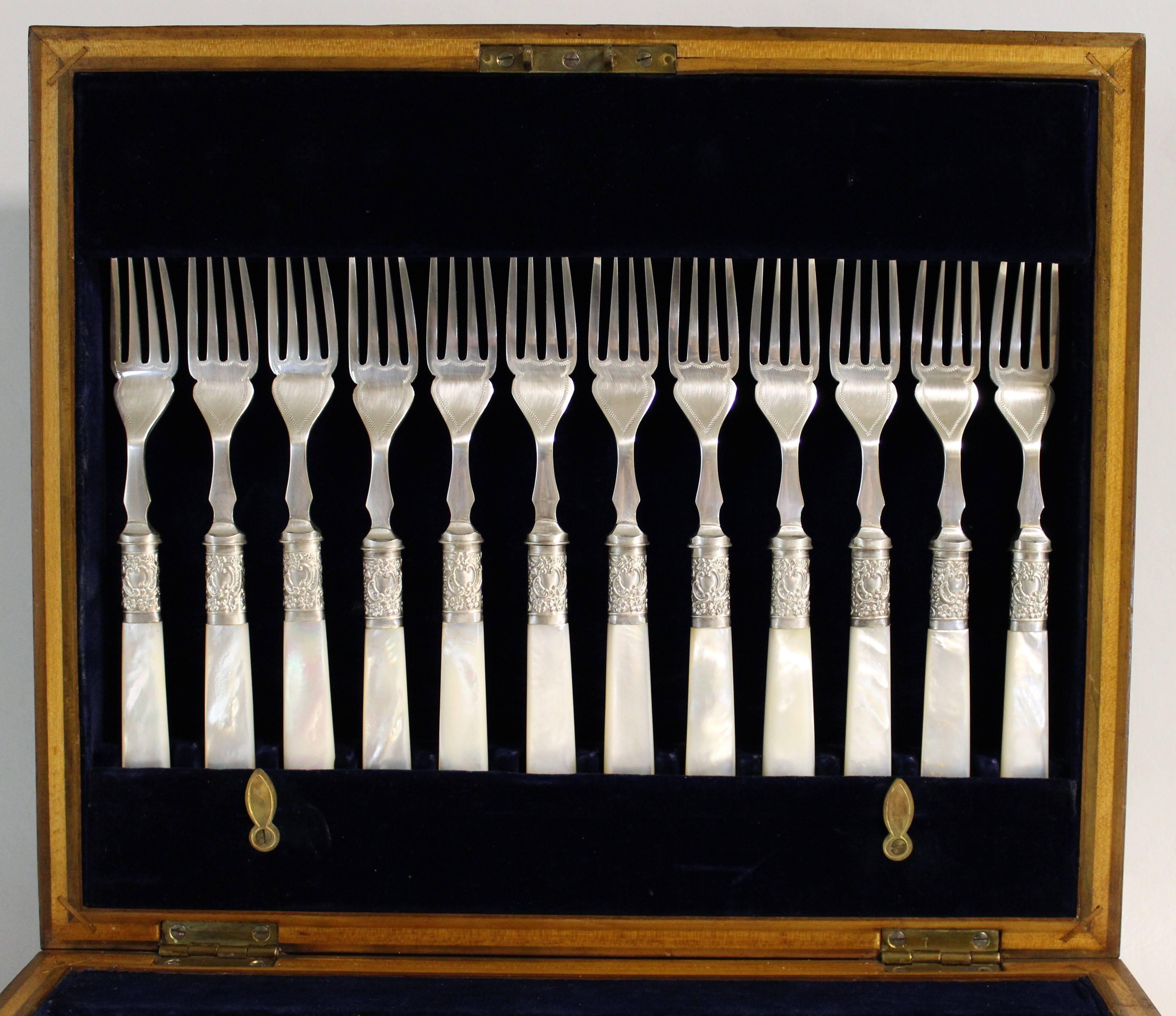 A beautiful Sheffield silver plated silverware set. This set contains 12 knives and 12 forks with decorative engraved blades, long reeded ferules and real mother-of-pearl handles. In the original wood box with blue velvet lining and original key.