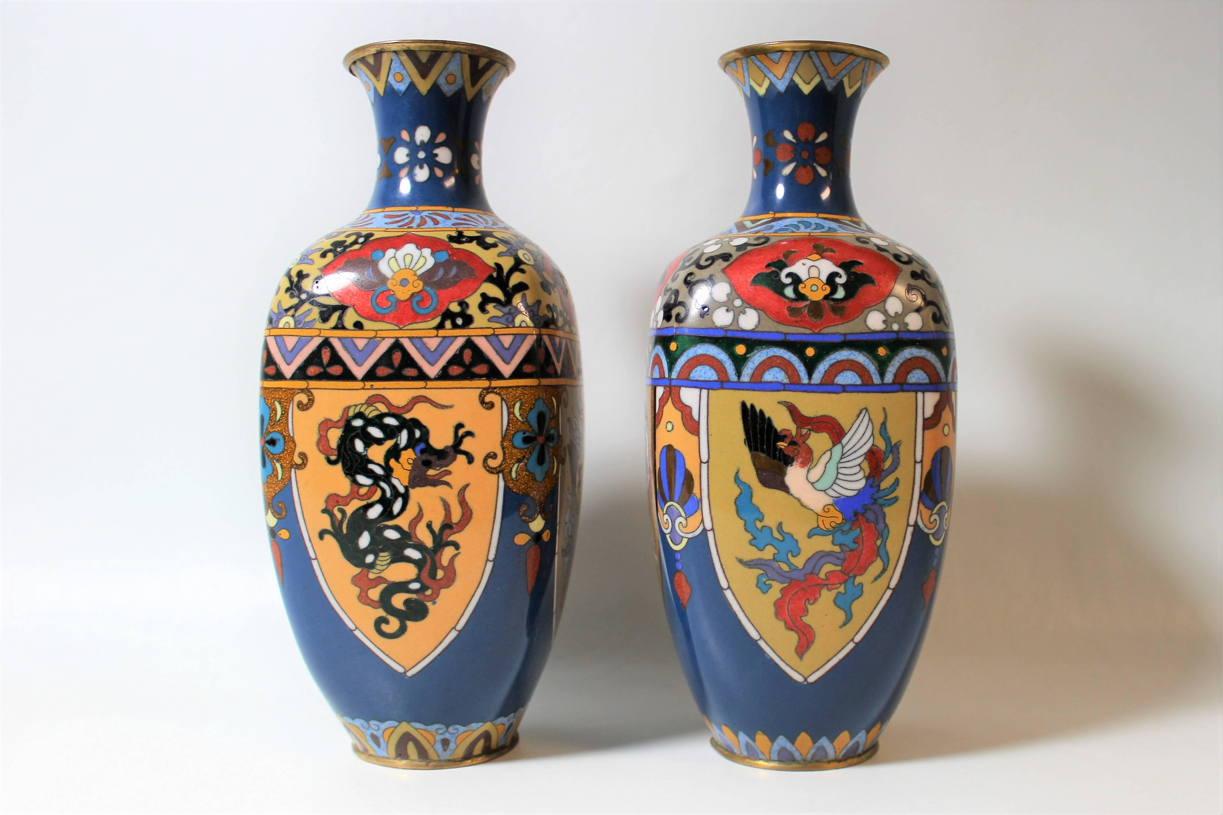 Pair of Japanese cloisonne vases dating to the late Meiji period. Each vase is decorated with matching designs of dragons and phoenixes around the body.