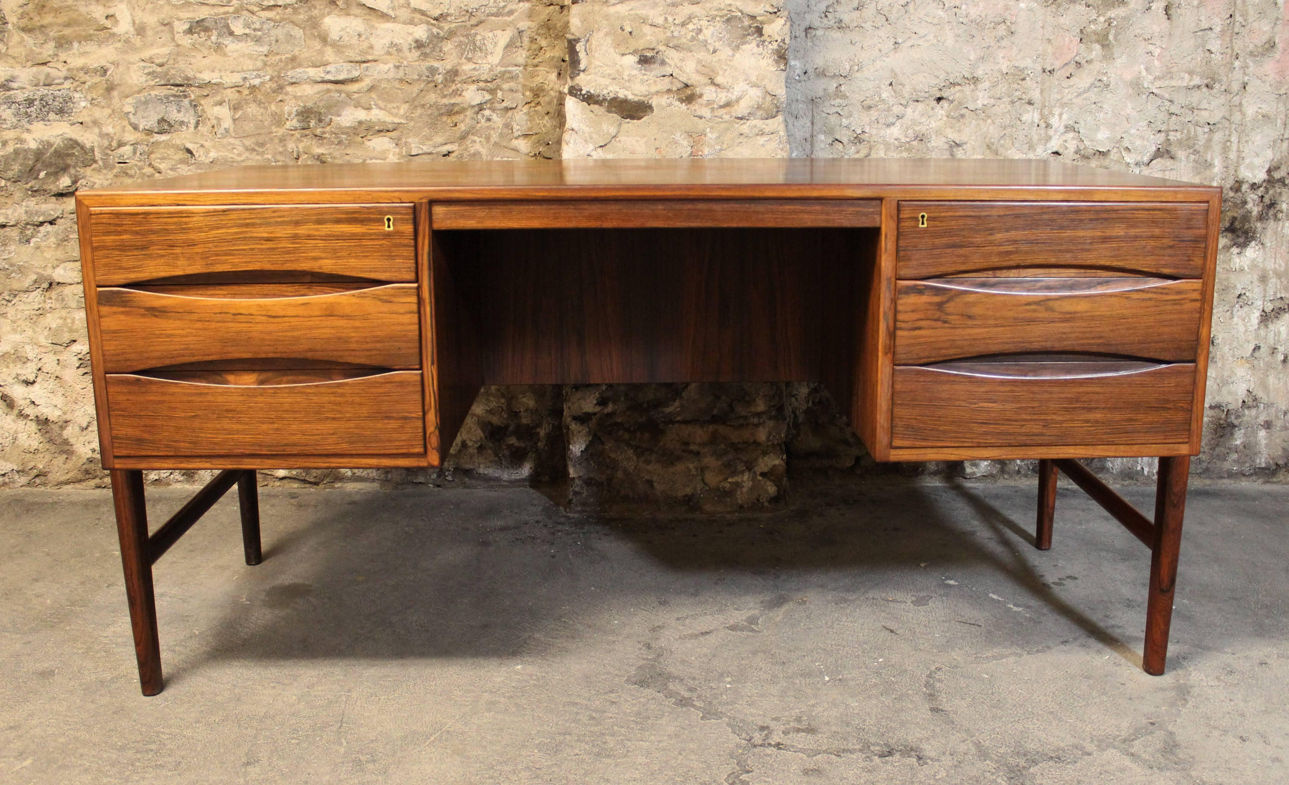 This Danish modern floating top desk in rosewood is the perfect piece for any modern office. The knee hole is nestled between two banks of three drawers. Deep drawers extend the depth of the desk and offer a finished back allowing this piece to be