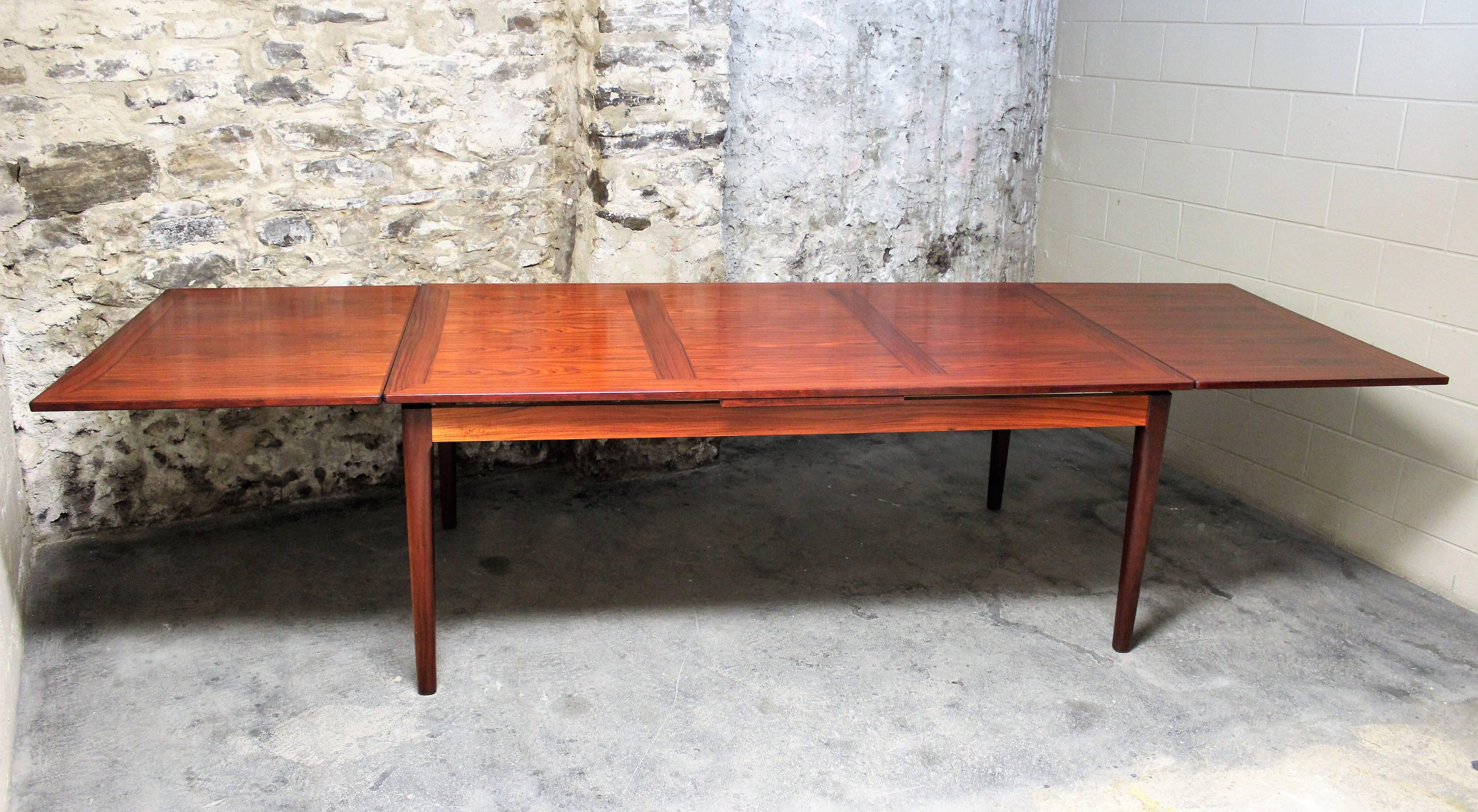 An exquisite Danish modern dining room or conference table by Skovby Mobelfabrik of Denmark. It features stunning Brazilian rosewood grains and two leaves which are stored inside the table. It measures ten and a half feet long with the leaves out