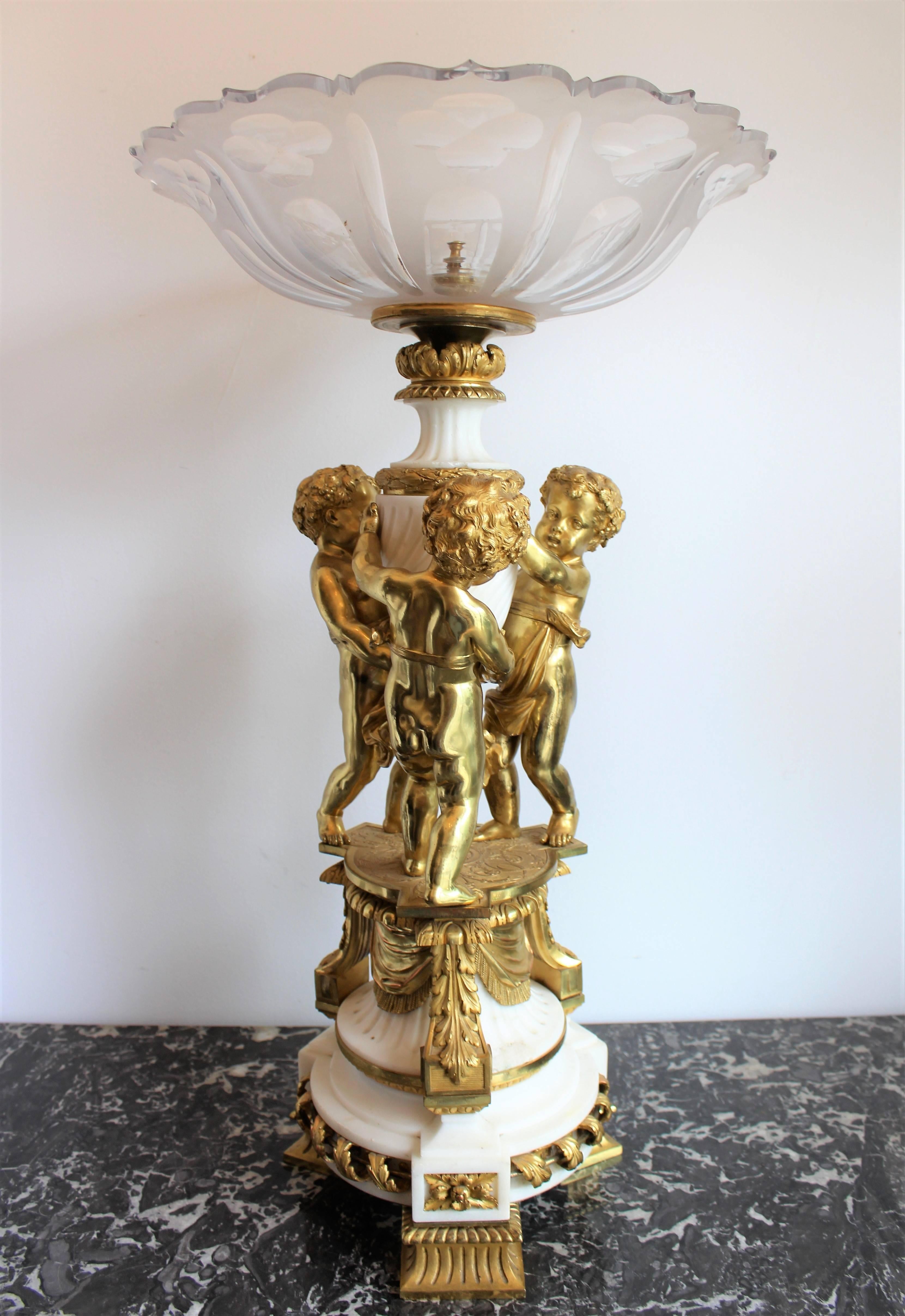 19th century French Louis XVI style gilt bronze, marble and crystal centerpiece. The heavy etched crystal dish held aloft by three putti holding up a marble column over a highly stylized base.
