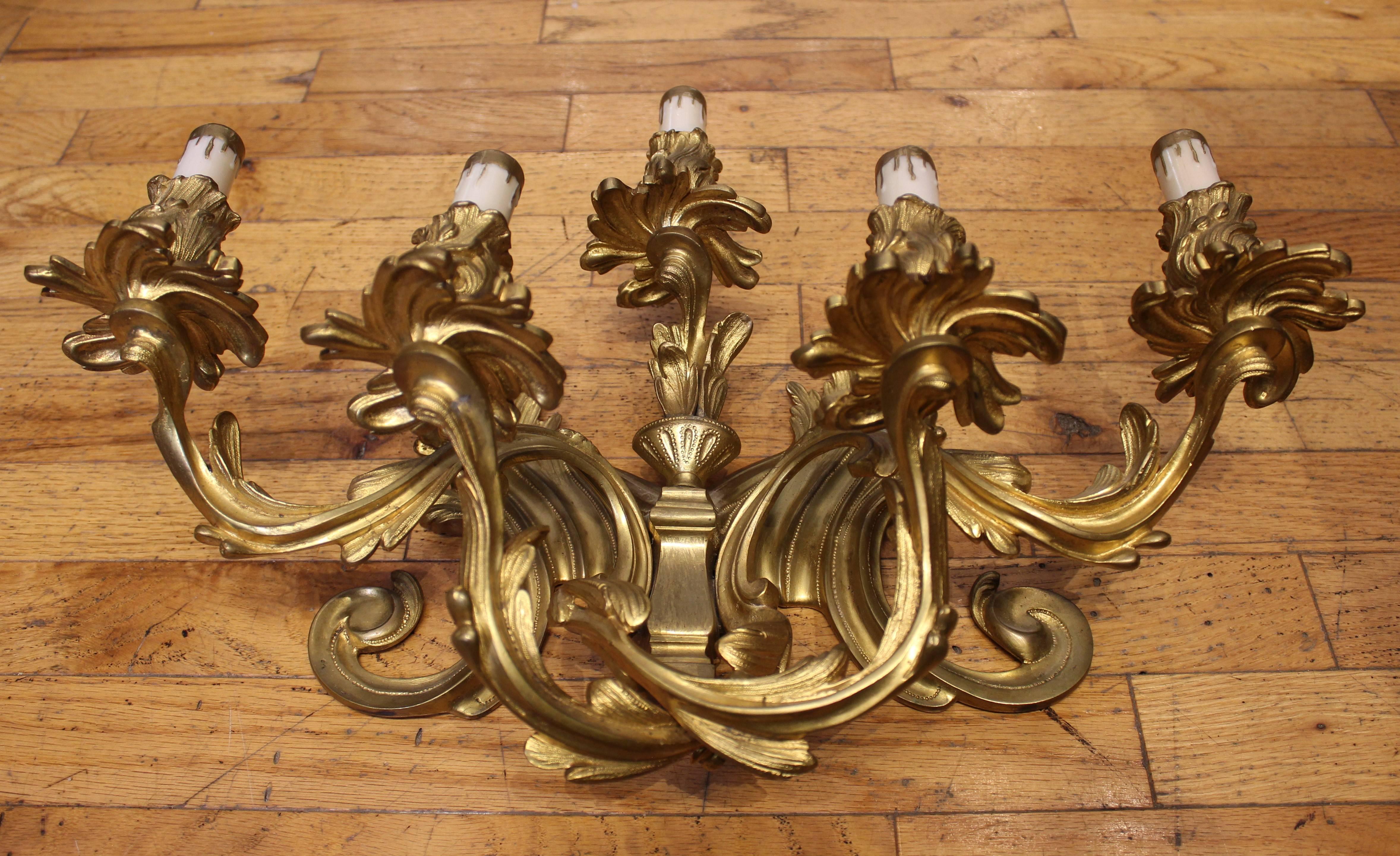 Superb pair of large Louis XV style gilt bronze wall sconces. Each sconce features five branches of lights that are sculpted with acanthus leaves, asymmetric scrolls and gadrooned foliage. Re-wired to North American standards.
          