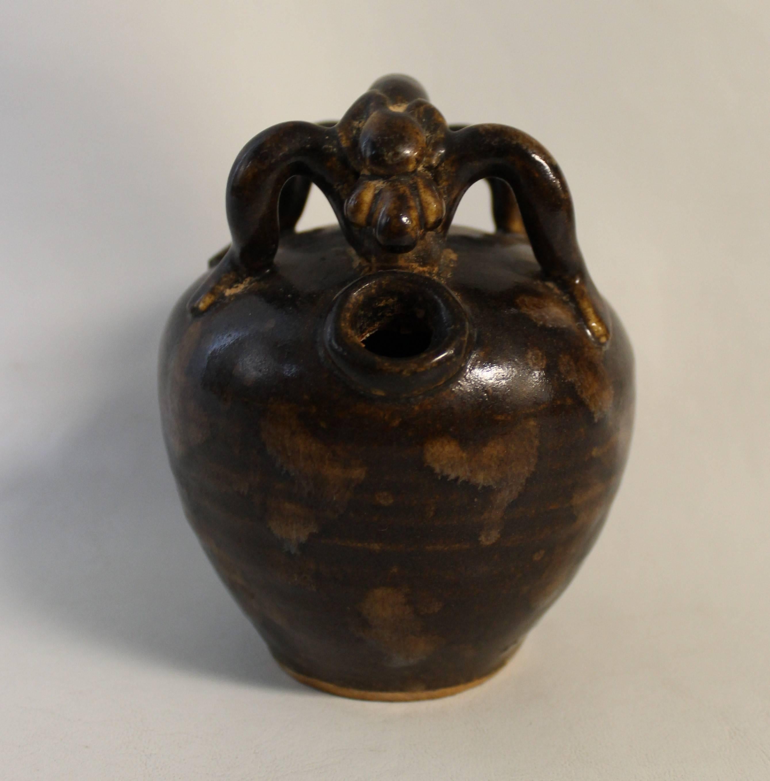 Early 20th century Chinese song style wine ewer or jar in tortoise shell glaze. It features an ovoid body and side opening with young mouth. The top is surmounted by a lizard-form qilong dragon on all fours guarding the mouth and finished in mottled