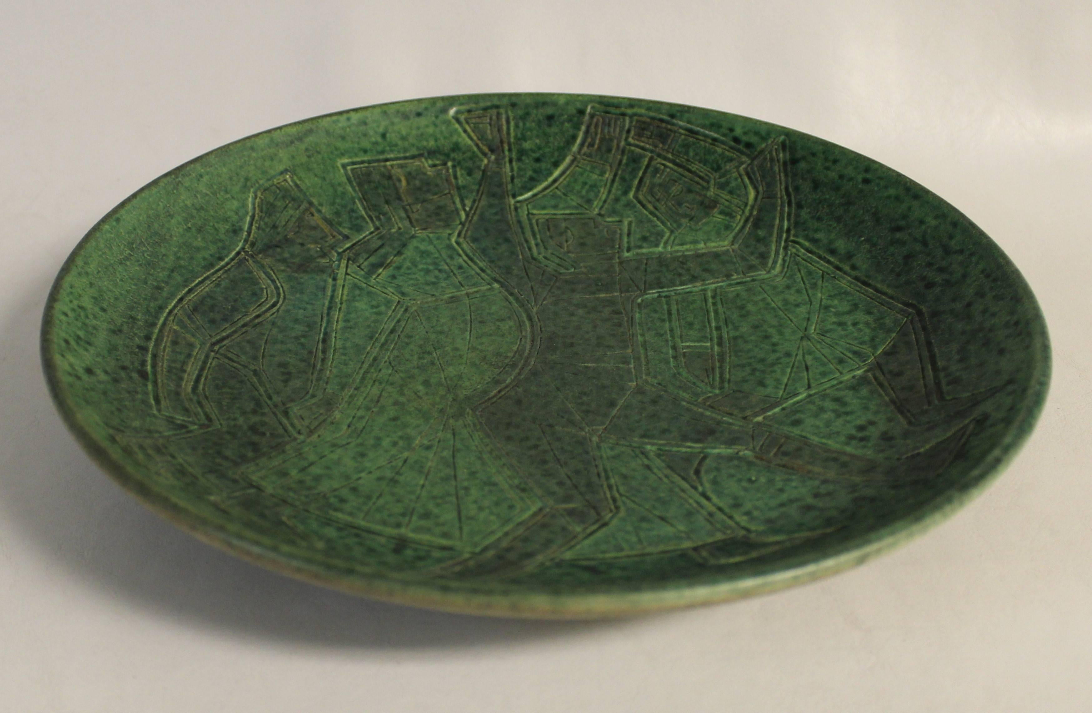 Studio Pottery Mid-Century Modern plate by Theo and Susan Harlander of Brooklin Pottery, Brooklin, Ontario. This bowl was designed with a whimsical cubist flare with incized figures and a mottled green glaze finish. 

German immigrants Theo and
