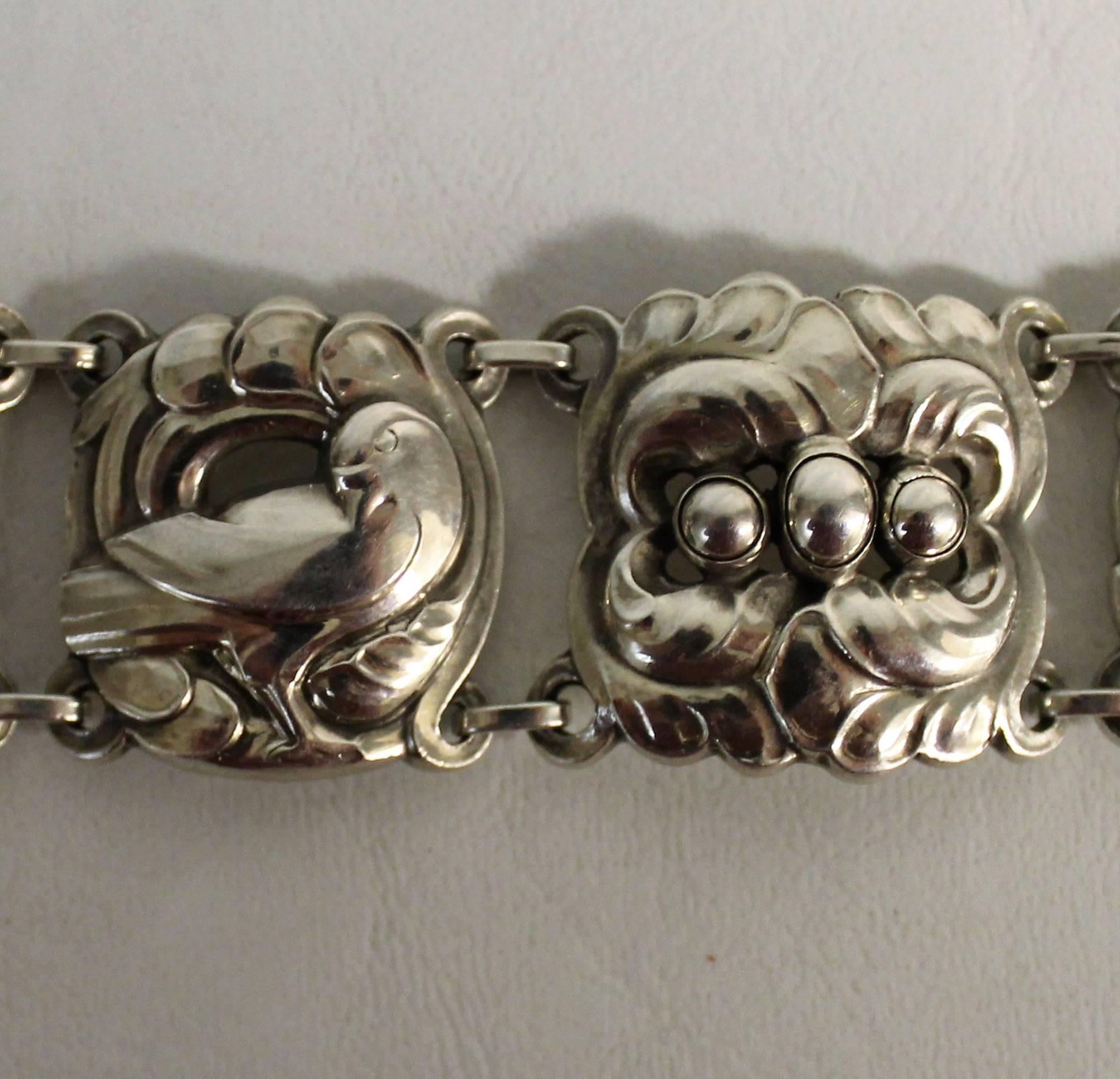 Ce superbe bracelet en argent massif est composé de maillons alternant des colombes et des œufs dans des nids. Il s'agit d'un design danois classique de Georg Jensen avec des influences Art nouveau. Il est doté d'un merveilleux système de fermeture