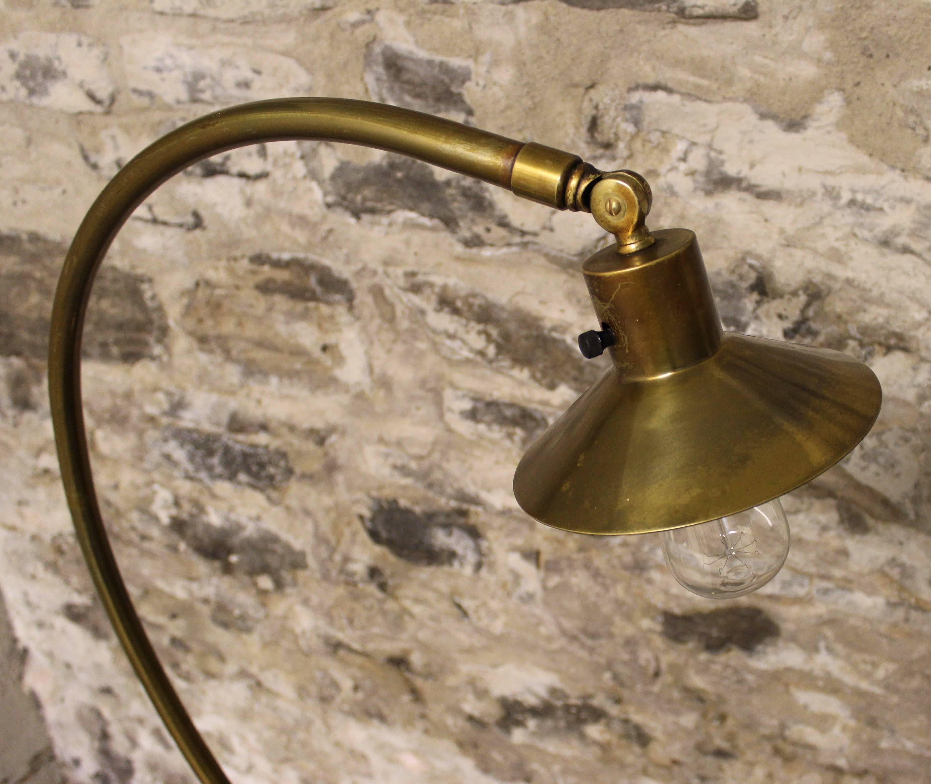 Industrial brass arc floor lamp with adjustable swivel head.