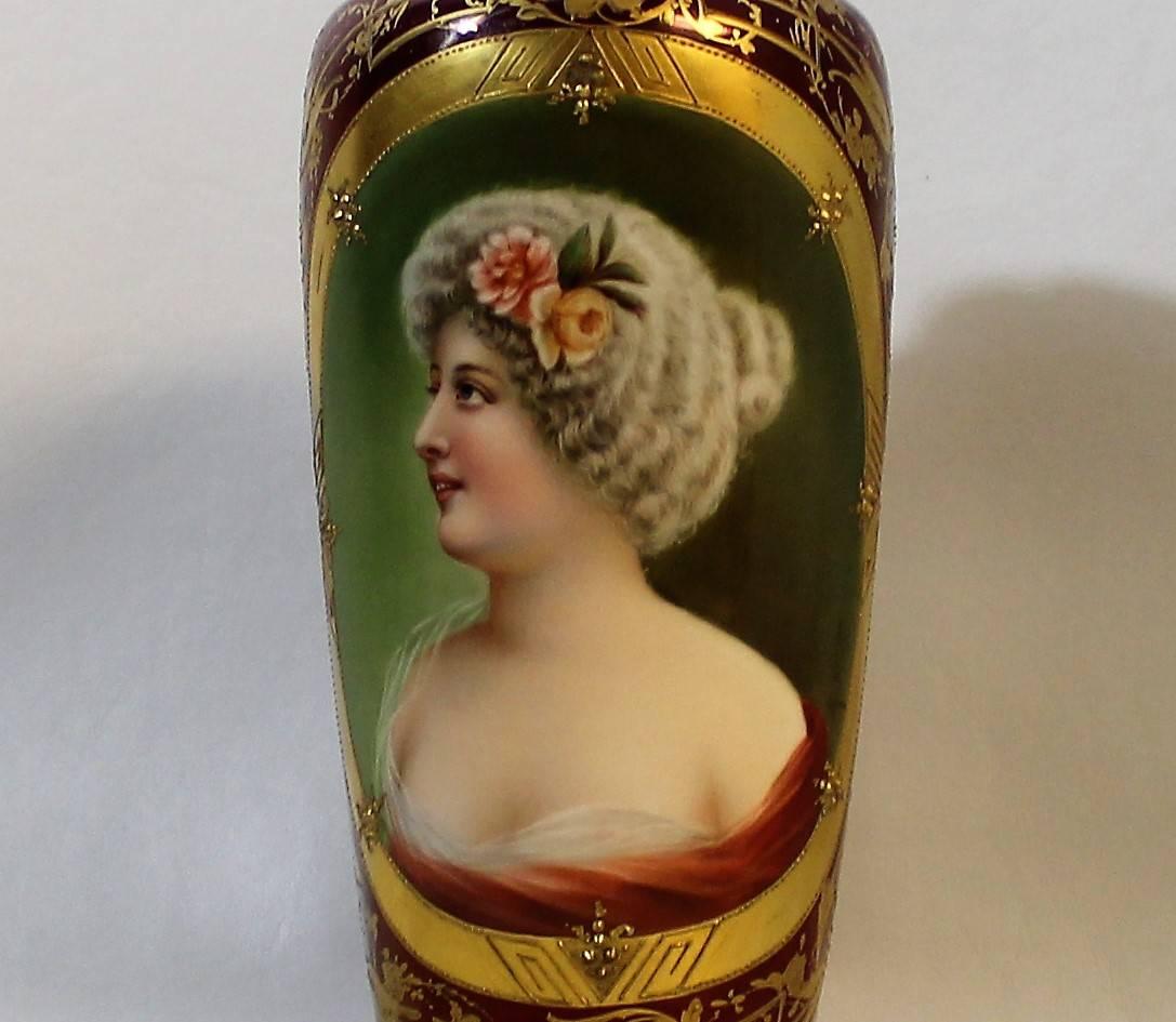 Royal Vienna style porcelain vase. The red body is covered with gilt and raised gilt Art Nouveau style floral decoration. The centre features an oval cartouche with a painting of a beautiful woman. The bottom is signed "Verrella" and