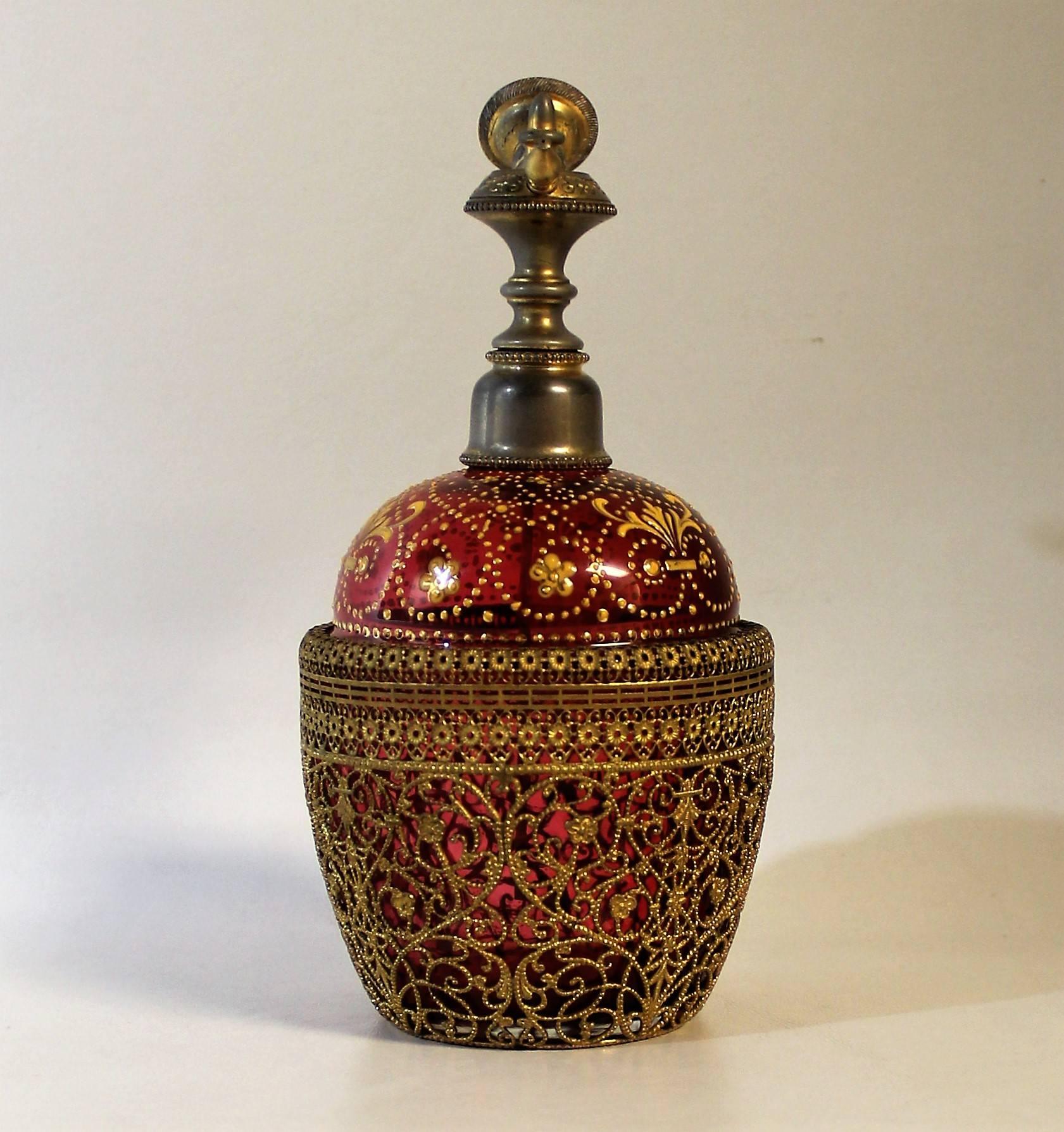 Cranberry glass perfume bottle with filigree and gold enamel.