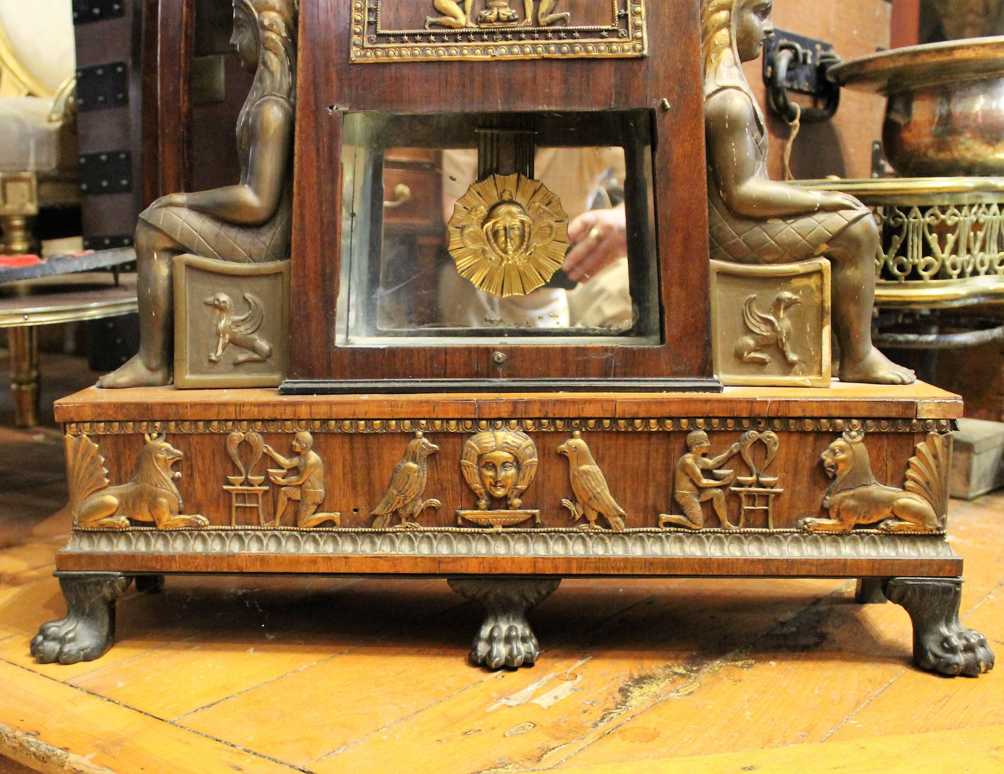 Egyptian Revival Grande Sonnerie clock from the Biedermeier period. It features animated workmen that swing an anvil, pump bellows while making a 'clack clack' noise.