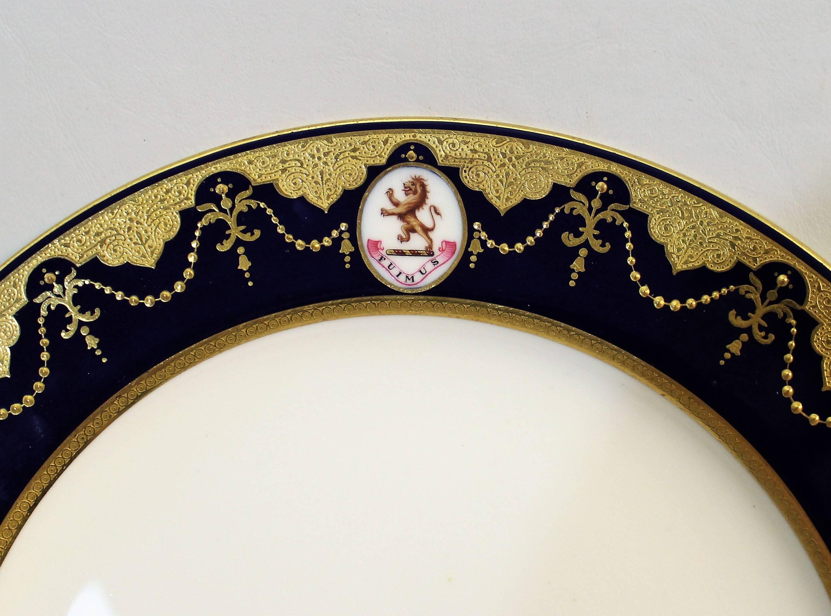 Set of eight Minton porcelain armorial dinner plates. These stunning plates feature raised paste gilt work accented with acid etched bands on a rich cobalt blue ground with armorial lion insignia bearing the motto 'Fuimus'. Measures: 10.25