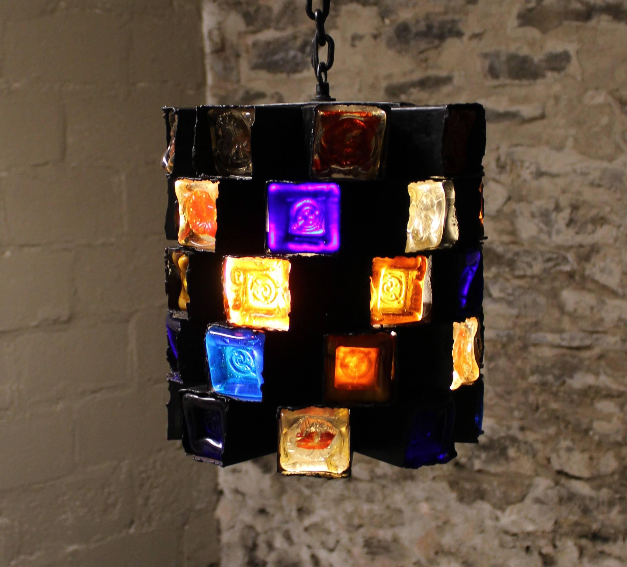 Brutalist iron and multicolored blown glass chandelier by Felipe Delfinger for Feders. Each modernist cube is hand-wrought in black iron which cradles the thick sculptured glass.