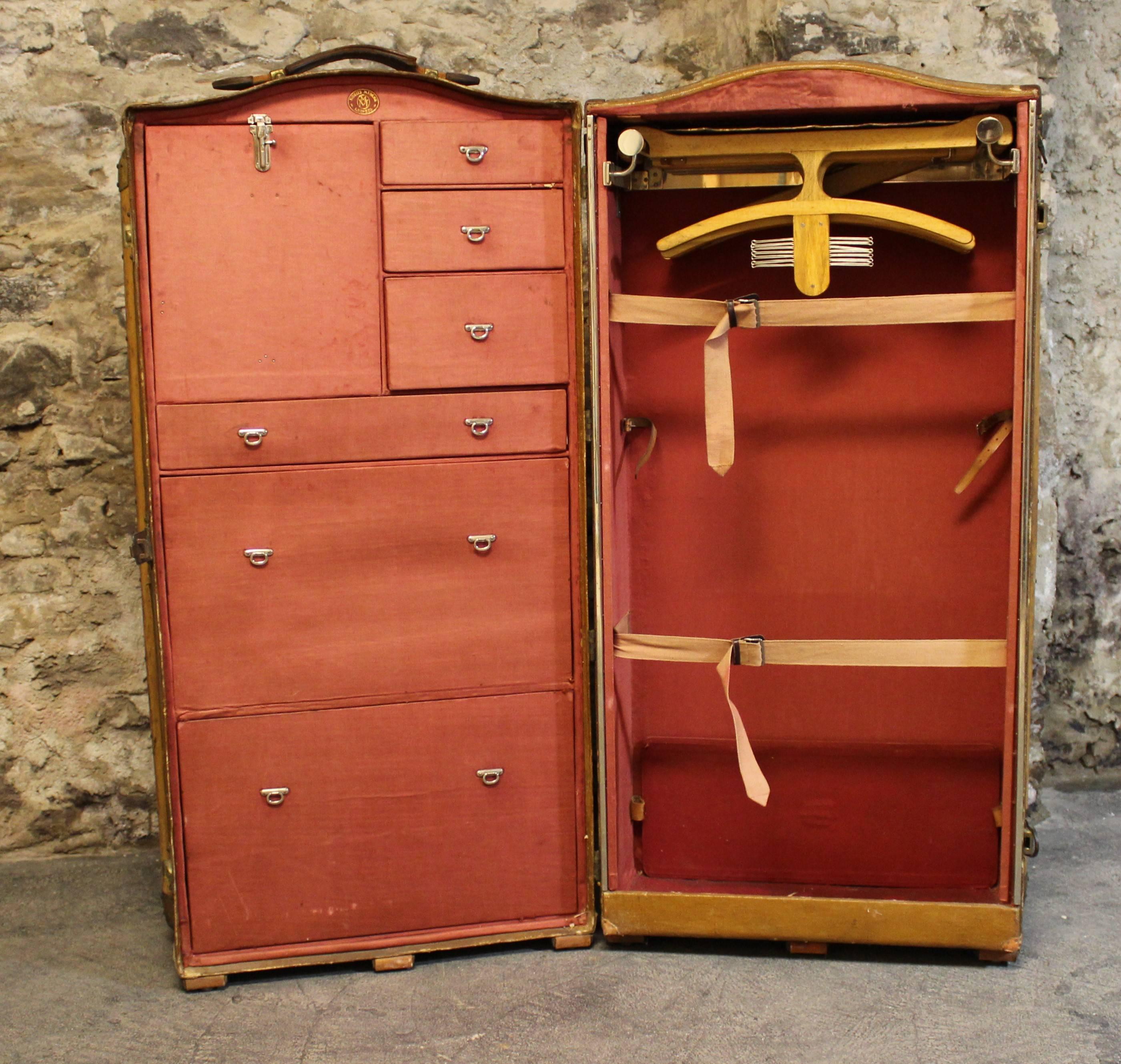 Moritz Madler double wardrobe trunk travelling suitcase.  The exterior is trimmed with leather, wood and brass hardware and it opens to an interior that holds multiple drawers on the left side and a hanging closet on the right. This beautiful German