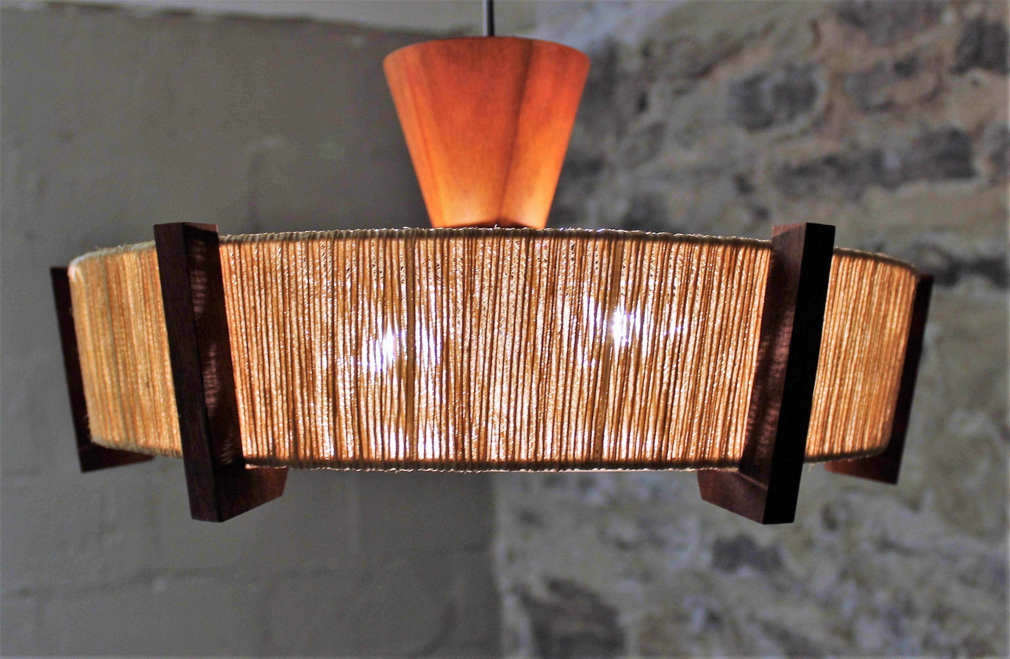 Danish modern pendant and ceiling lights made from teak and woven jute. The pendant’s height is easily adjustable with a pull system designed to slide up and down. It will hang anywhere from 20" - 60" off the ceiling. The ceiling light is