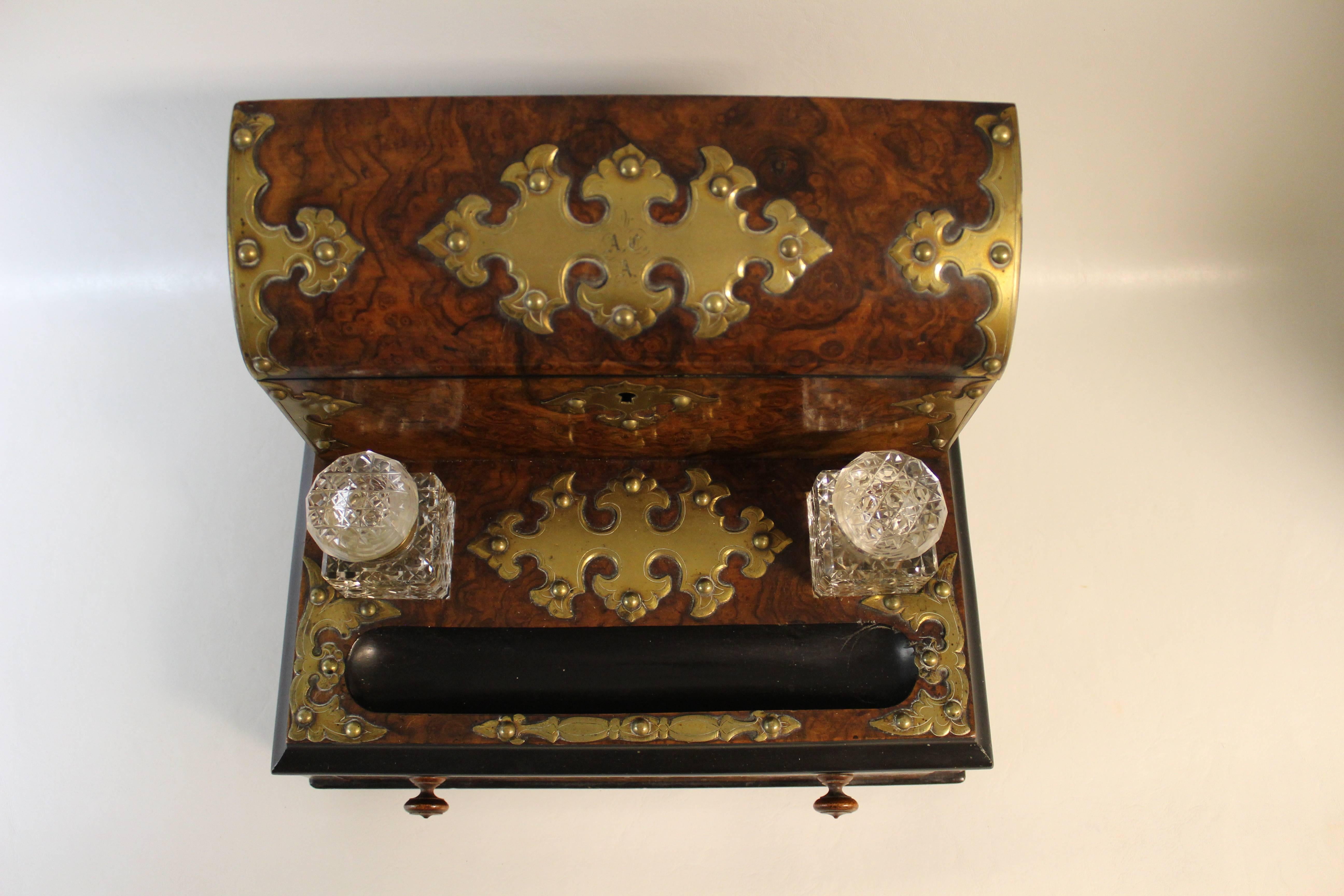 English stationary box made of burl walnut with chased brass mounts. This lovely victorian box opens to reveal fitted compartments and a royal blue moire silk lining inside the top. The base of the desk set is sitting on four turned feet supporting