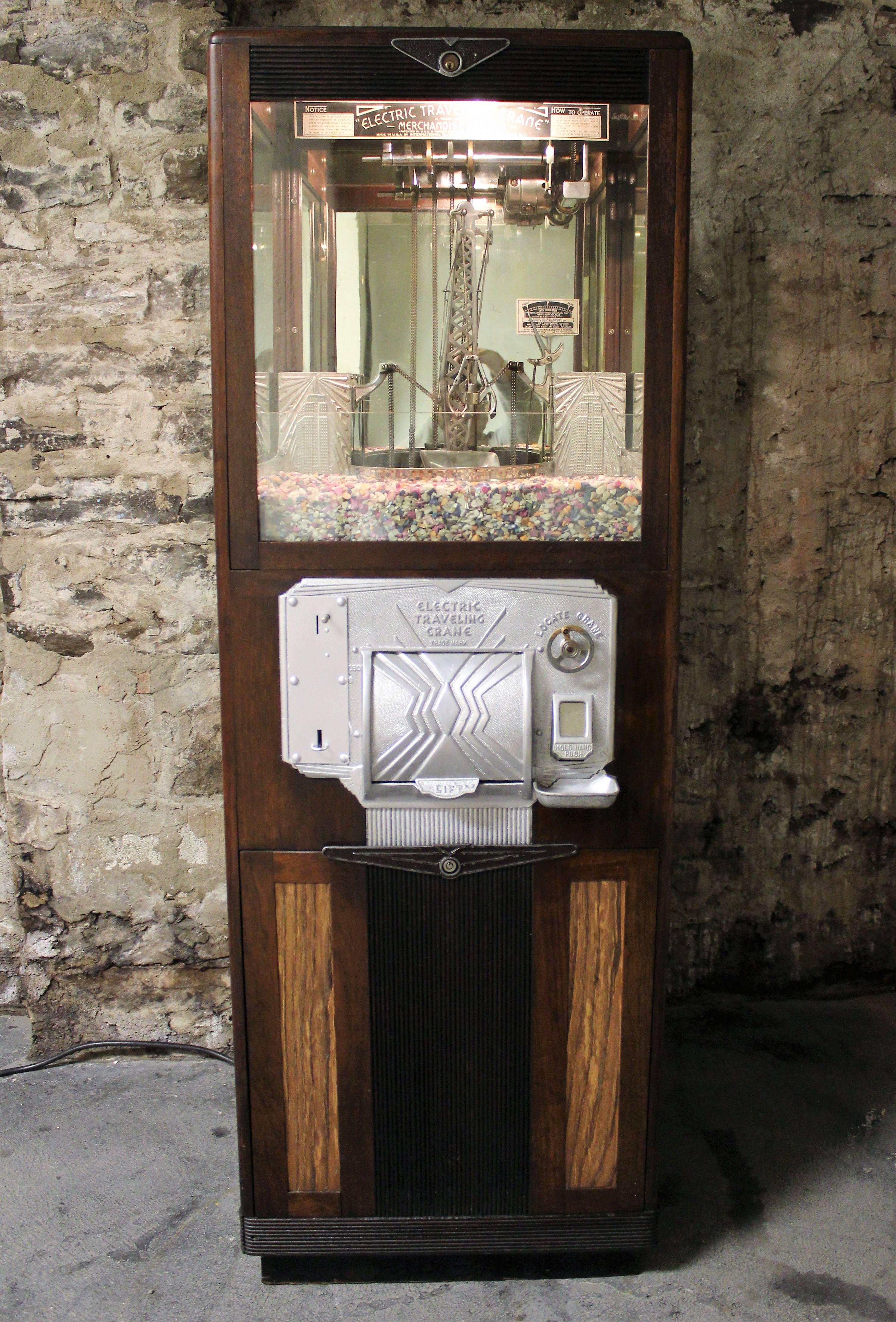 Floor-standing coin-op crane digger arcade game with three glazed panels enclosing the crane mechanism flanked by Dual skyscrapers, circa 1930s.