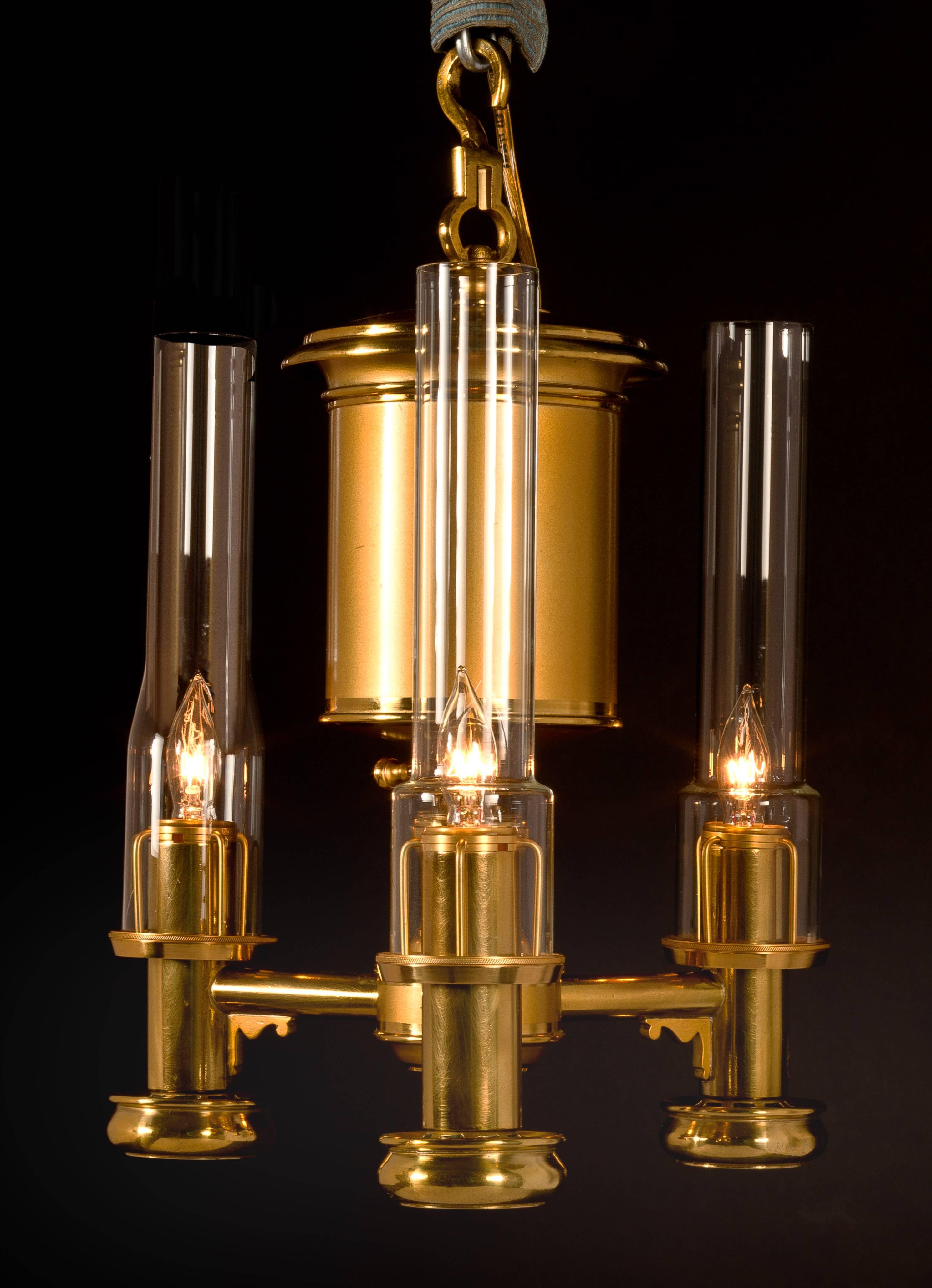 Labeled: Bright & Co./Late/ ARGAND & Co. / BRUTON St.
London, 1825-1830

The matte and burnished lacquered brass cylindrical oil font suspended from a brass loop and hook, with three fuel arms each with burner tubes with drip cups, the font with