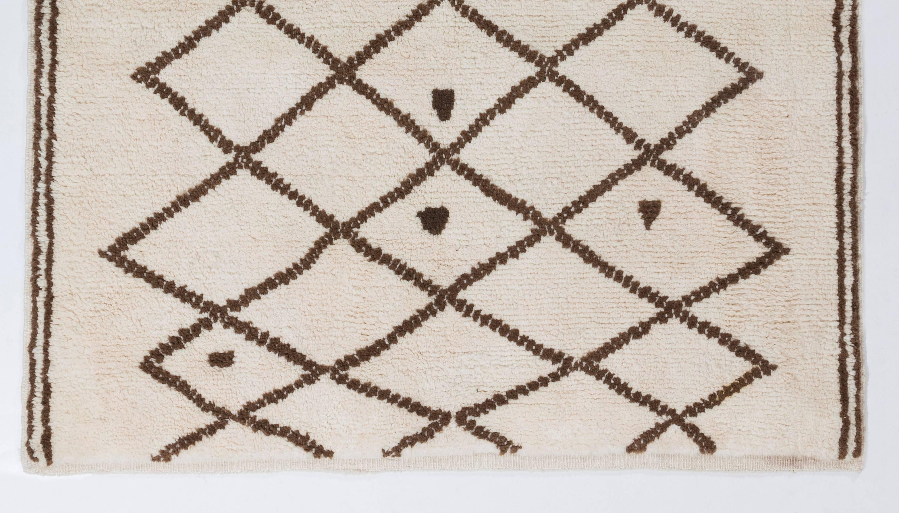 Dieser charmante marokkanische Teppich zeigt ein Gittermuster auf elfenbeinfarbenem Hintergrund. Er besteht vollständig aus ungefärbter, natürlicher Schafwolle, hat einen üppigen, weichen Flor und fühlt sich unter den Füßen gut an. 

Der Teppich