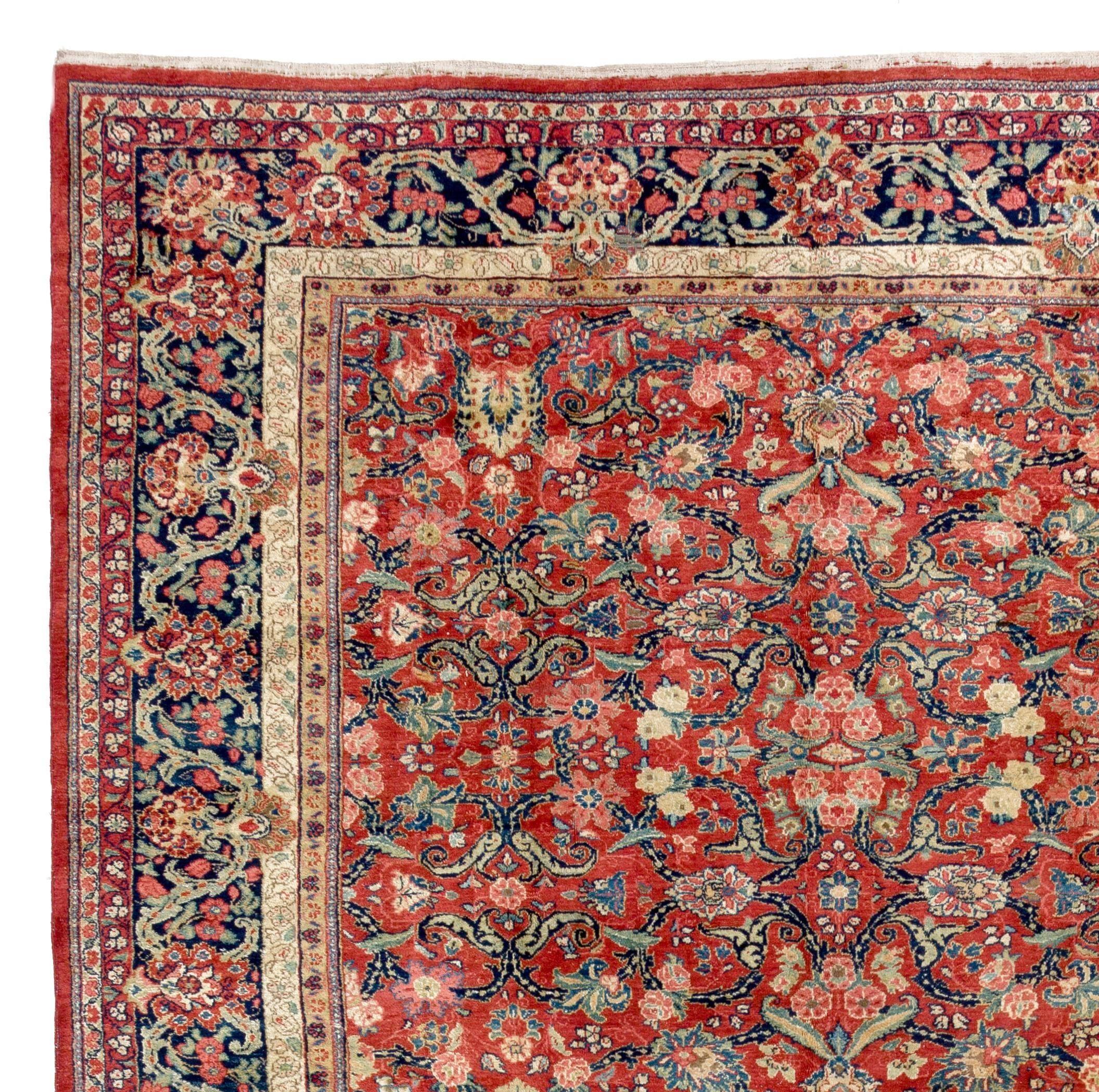 Large antique Persian Mahal carpet.
Measures: 11 x 18.4 ft.
This elegant rug has a madder field infused with a soft red hue featuring an overall design of scrolling lobed floral vines, palmettes and curling leaves framed by a dark indigo border of