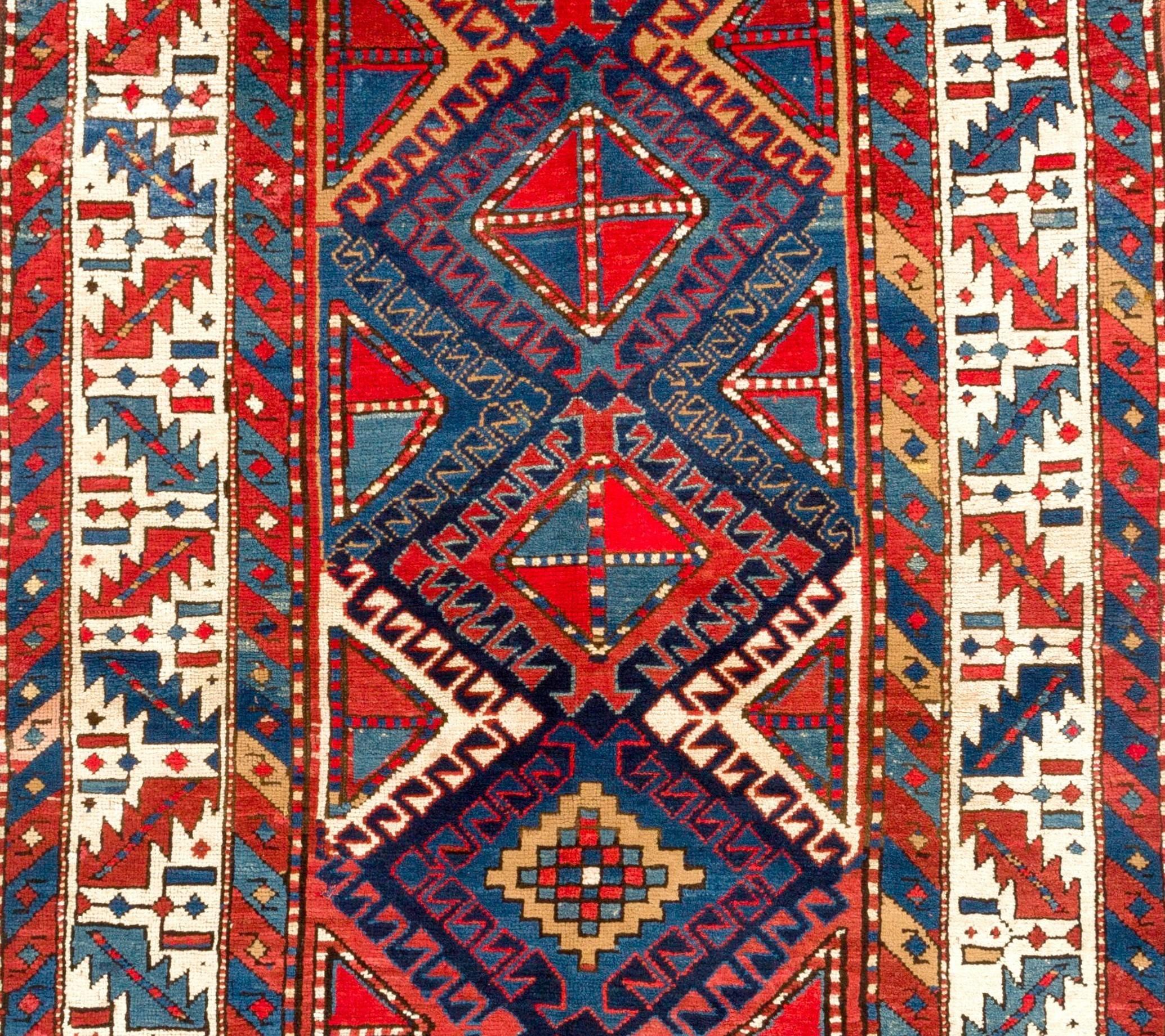 This truly vibrant, antique Gendje Kazak long rug from central Azerbaijan in the south Caucasus features a strongly geometric field format composed of an array of hooked diamonds with varying centers, all surrounded by a Classic wine glass and
