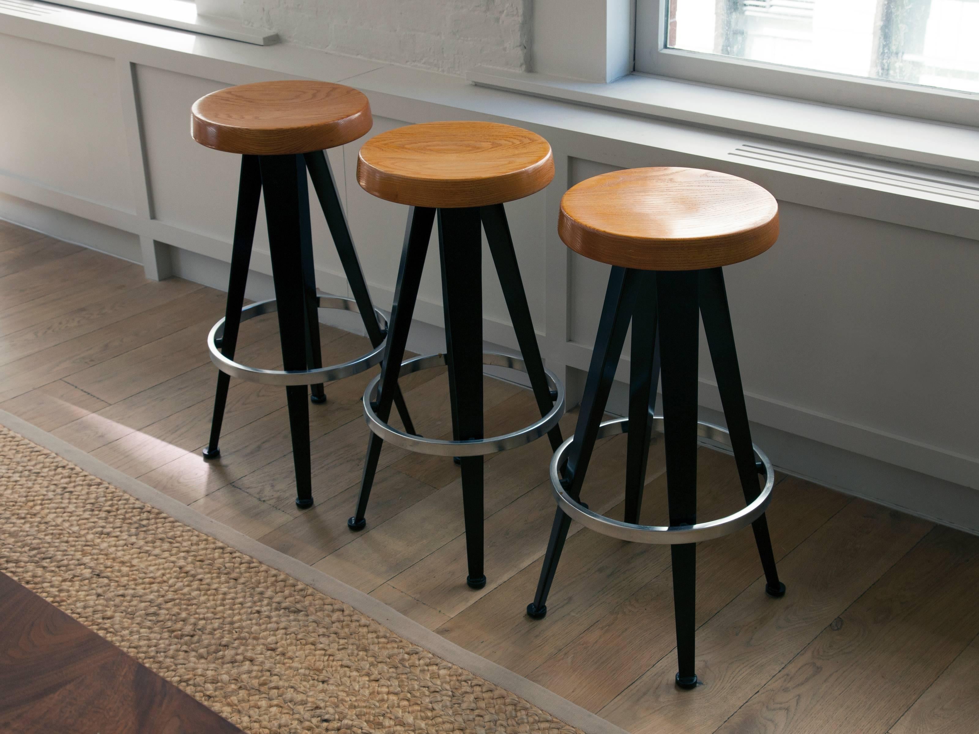 Set of three oak and steel counter stools produced after a design by Jean Prouvé in France. Provenance: Wright, Chicago. Sold only as a set.