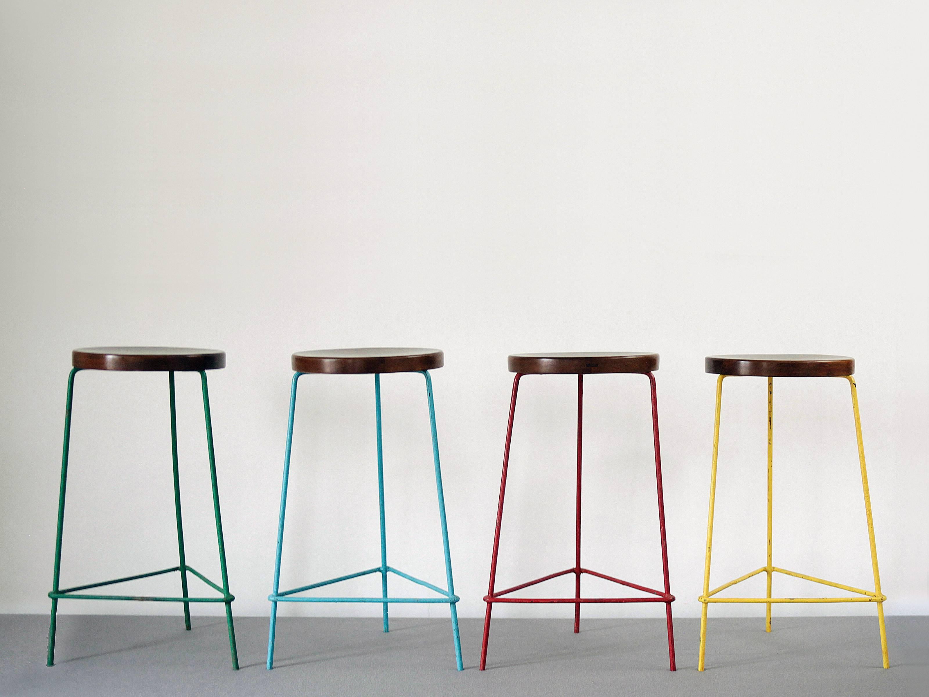 Set of four stools in red, yellow, blue and green from The College of Architecture, Chandigarh by Pierre Jeanneret. Beautiful patina.