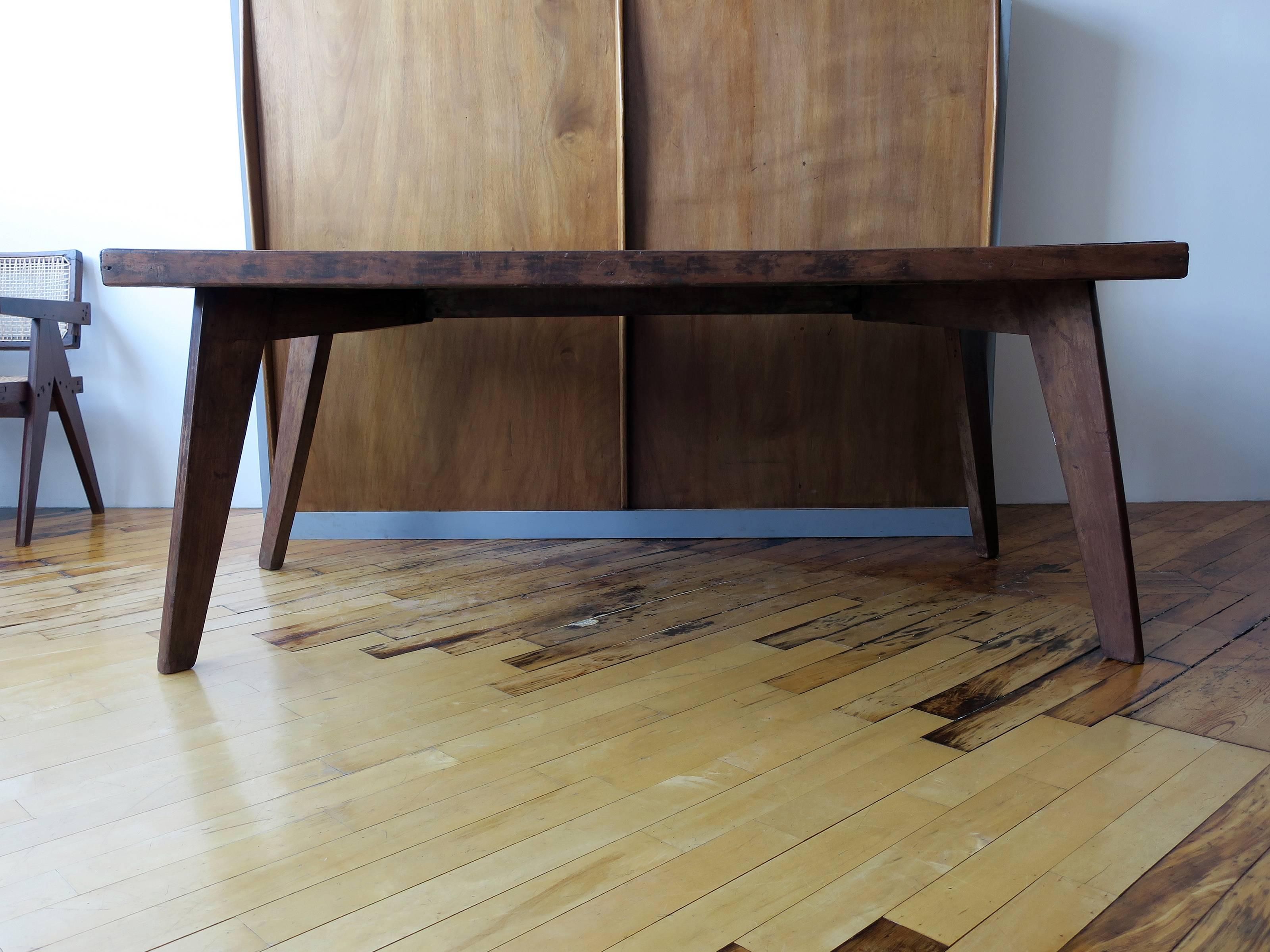 Teak dining table by Pierre Jeanneret from Chandigarh, India. Thick teak tabletop and legs, all in original condition, showing rich patina resulting from original use. Partial black painted lettering evident on one leg.
 