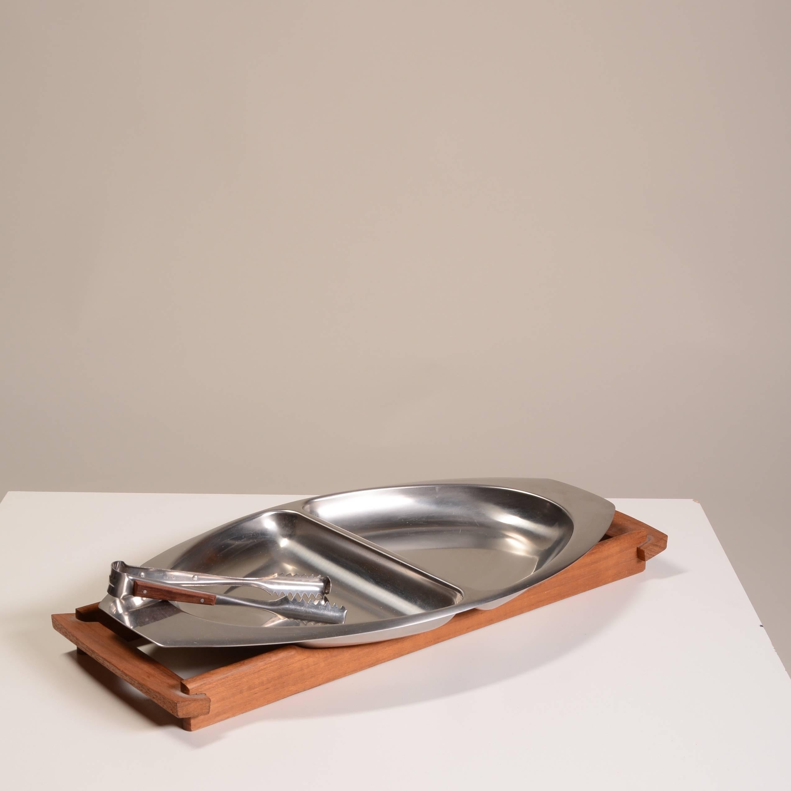 Vintage Mid-Century Modern Danish modern Kalmar designs three-piece stainless steel and teak serving tray.

Three pieces include one large divided serving tray, accompanied by a teak base and serving thong. Think festive entertaining and a mix of