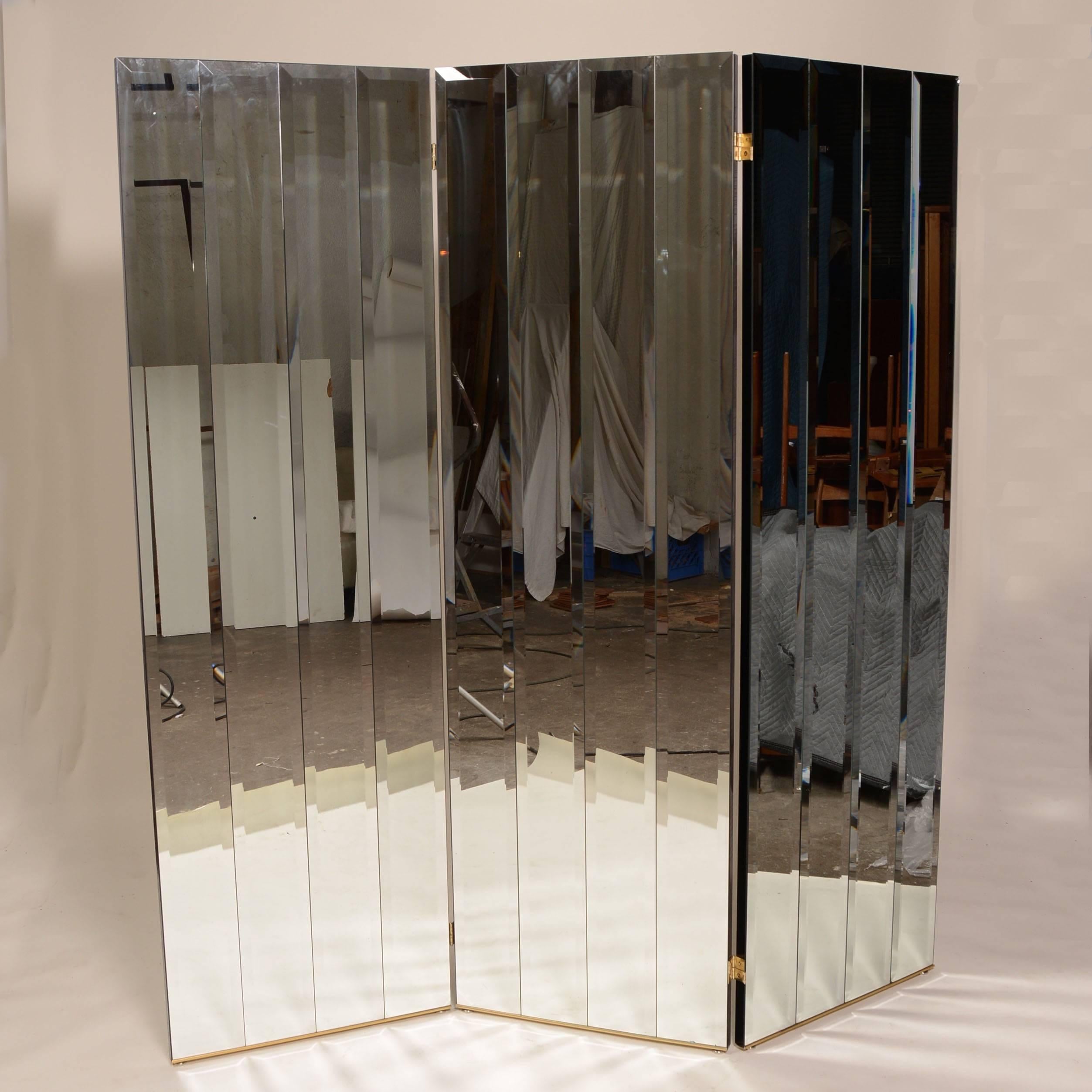 This is a rare Henredon three panel beveled mirror room divider, circa 1975. It features four separate beveled mirrors on each panel, heavy panel construction with smooth glossy black finish on the back and sides and brass base frame. 