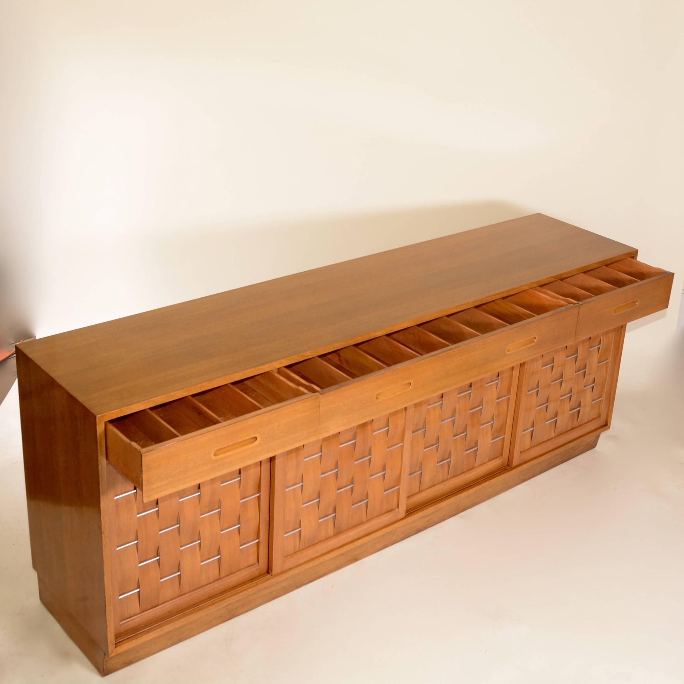 This is a rare ribbon mahogany and stainless steel basket weave front credenza by Edward Wormley for Dunbar. This piece retains its original Dunbar finish which is in excellent condition. Four sliding doors in front reveal an open cabinet in the