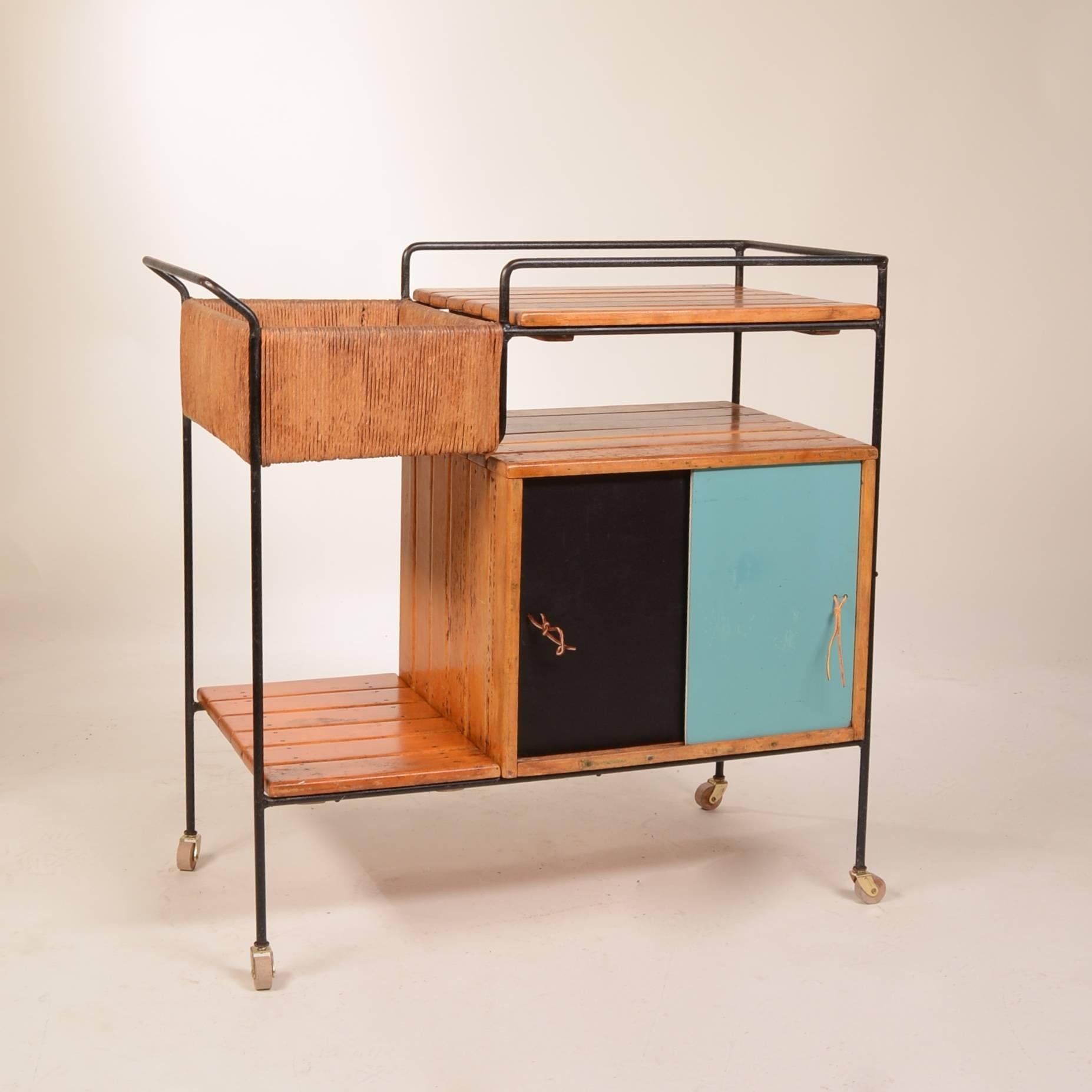Beautiful, modern bar cart by Arthur Umanoff. Features multi-material construction, including wood, iron and rush trim. Wonderful painted doors with leather pulls, this piece is out of this world!
 