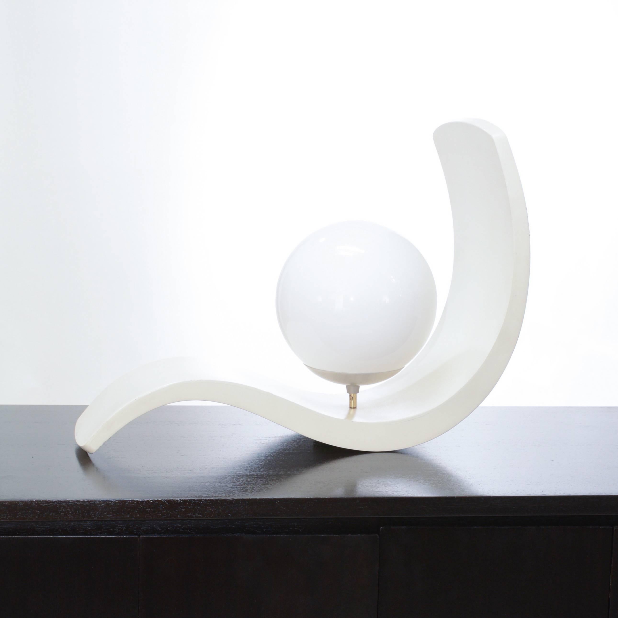 This beautifully crafted s-curved wood table lamp features a frosted glass globe and organic lines.
  
