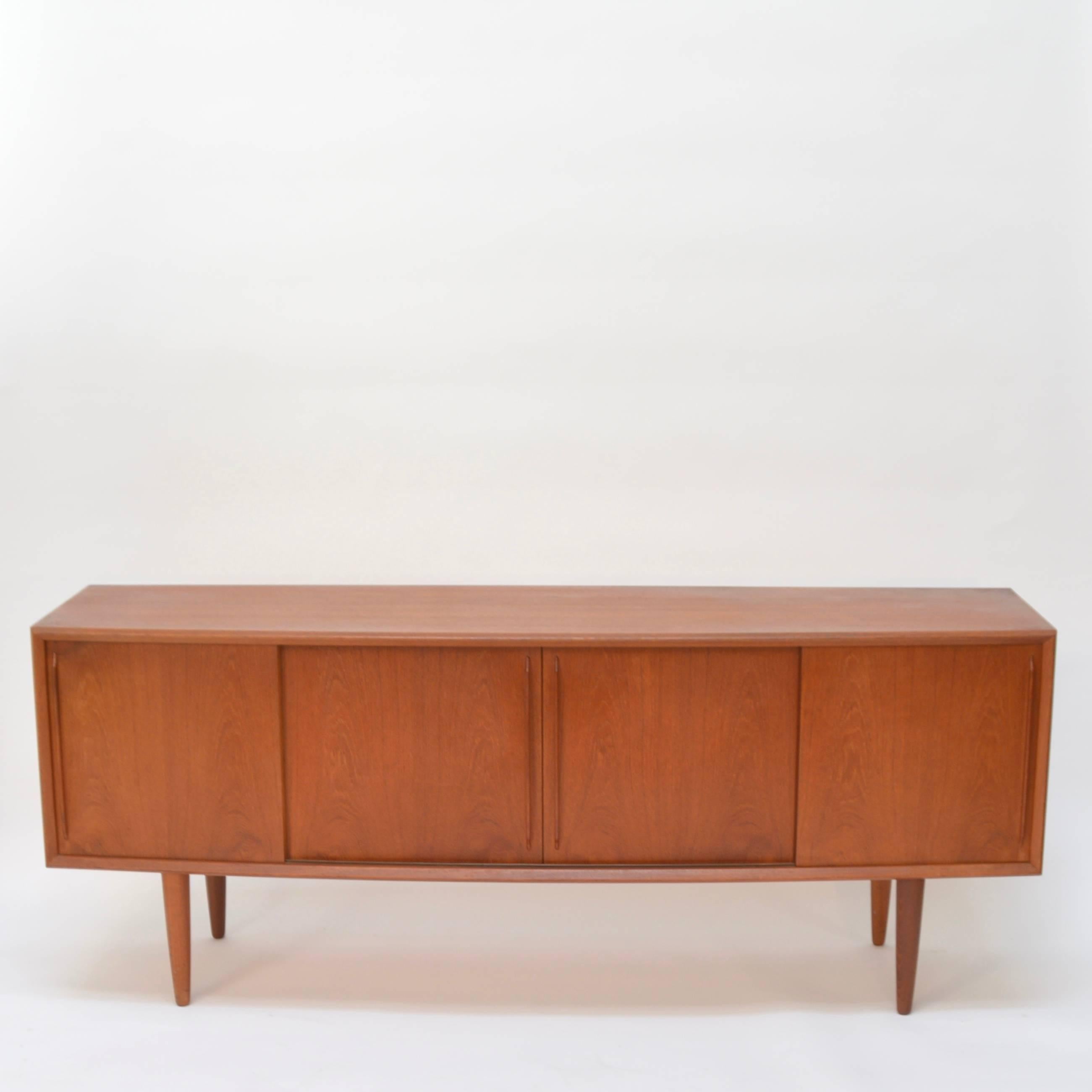 This is a unique curved front teak sideboard by HP Hansen or Denmark. This piece is in excellent vintage condition and retains its original oil finished.