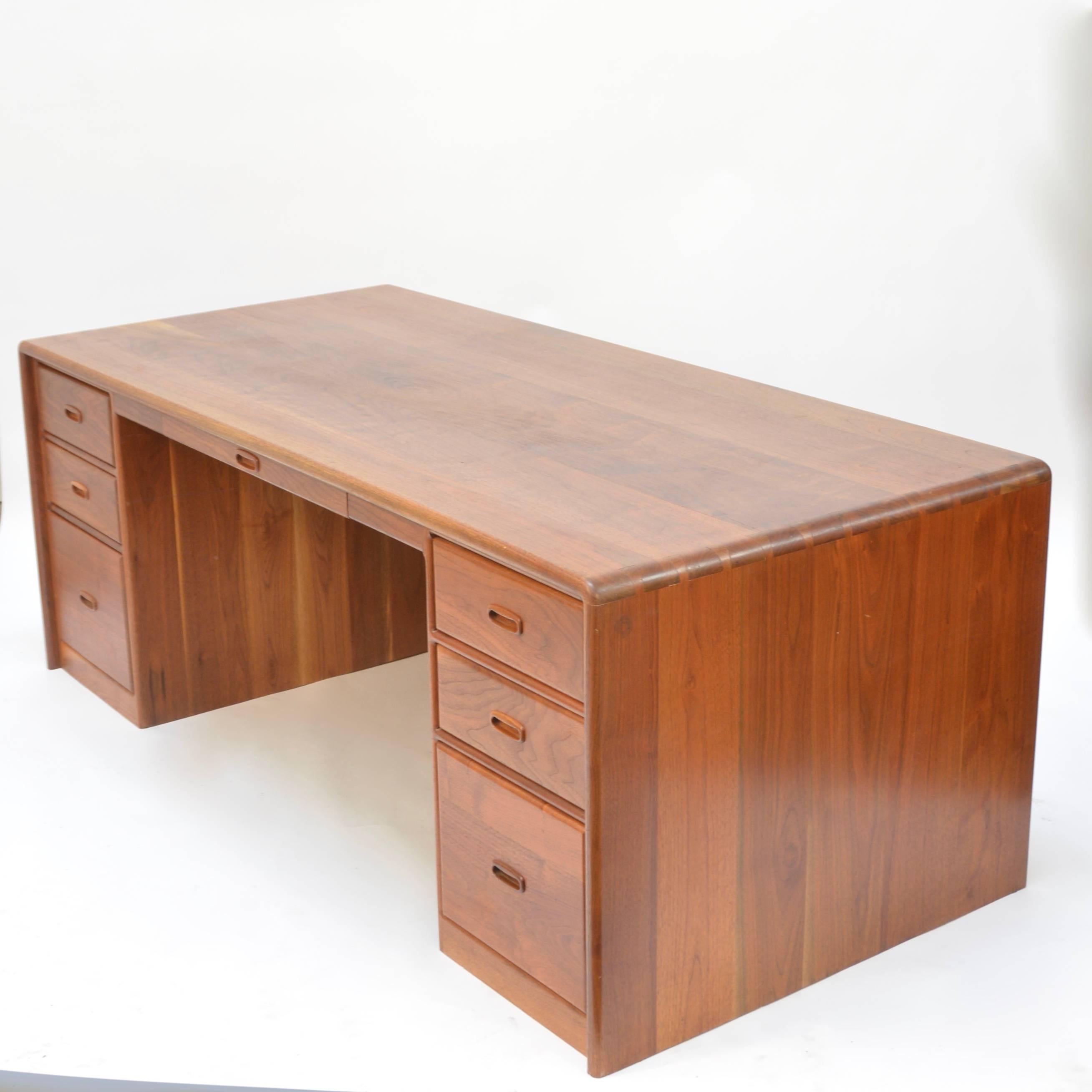 This is a custom handcrafted executive desk by Ed Rizzardi of Los Angeles. The desk features solid African walnut construction and beautiful joinery. This piece is in good vintage condition with light wear and some natural wood checking.