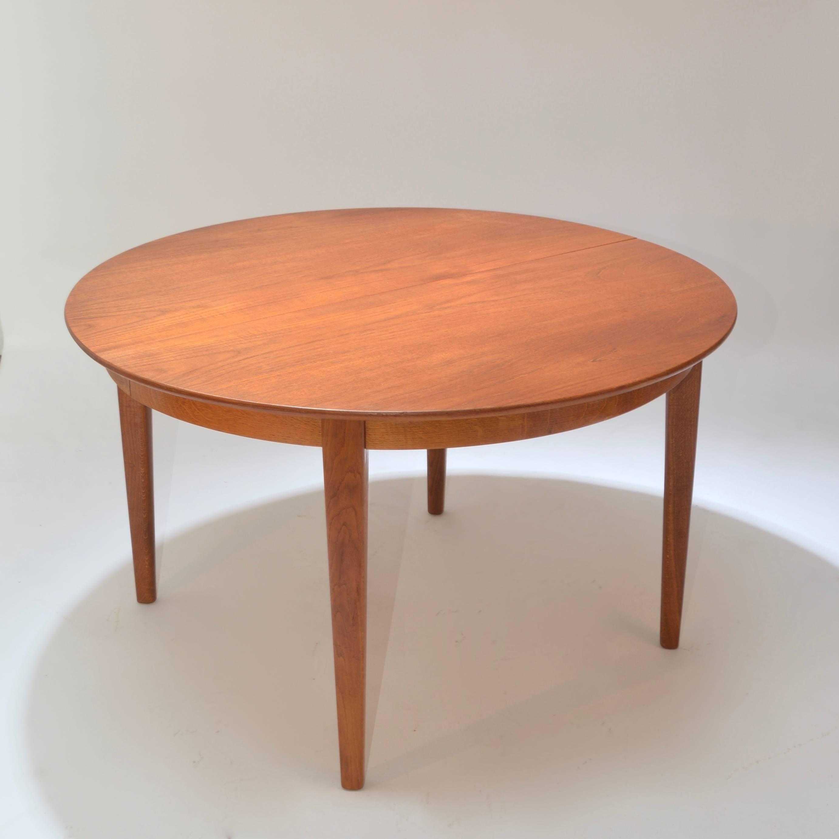 Beautiful Henning Kjaernulf teak dining table. This table was painstakingly handcrafted by the Danish maker Sorø Stolefabrik. Drop down center leg pops down when table is fully expanded. This table comes with one 20" leaf and can accommodate 3