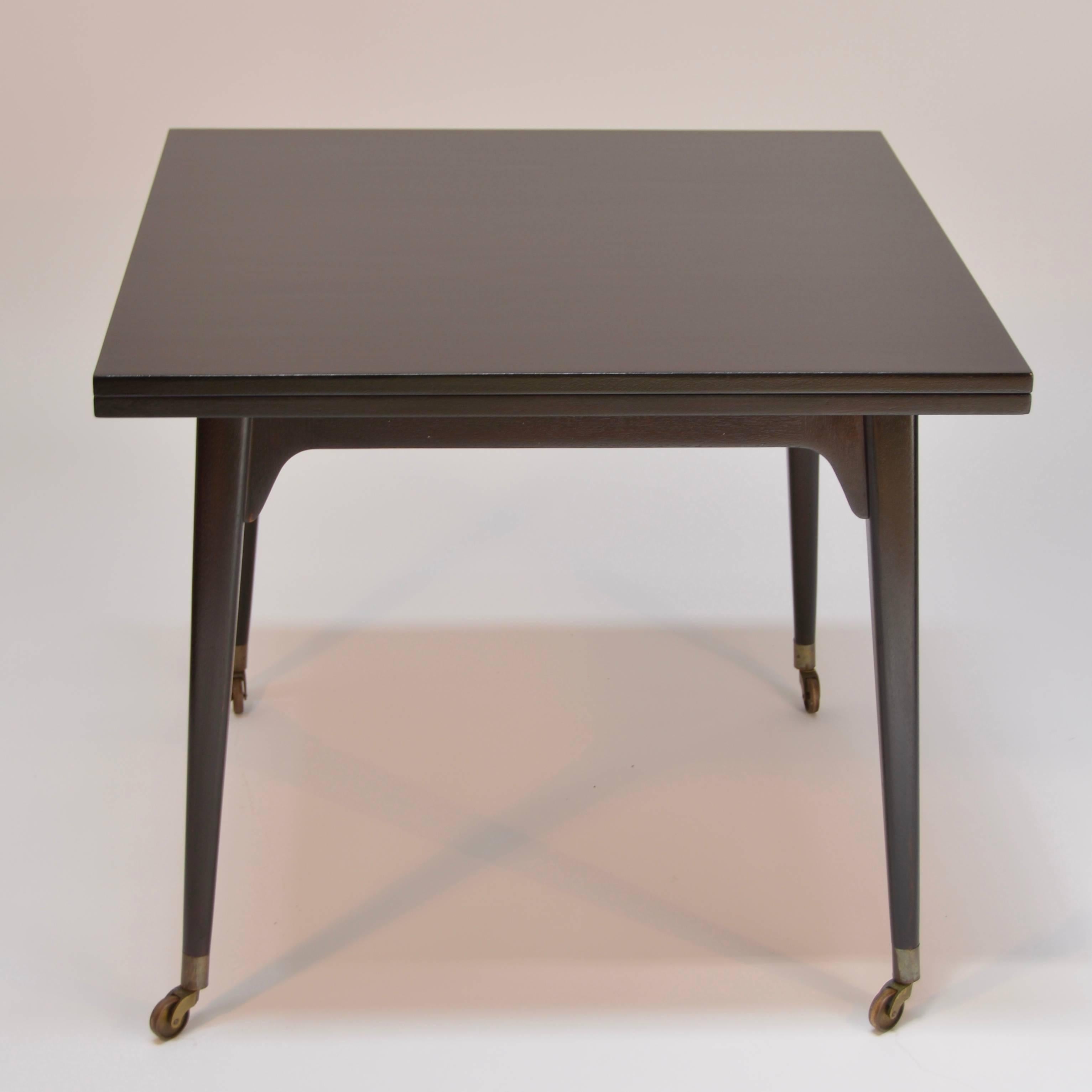 This is a restored Edward Wormley for Dunbar ebonized mahogany, flip-top game table. Top pivots and unfolds to 68" wide and can easily be rolled on brass castors. Also includes a large storage area for all of your gaming needs.