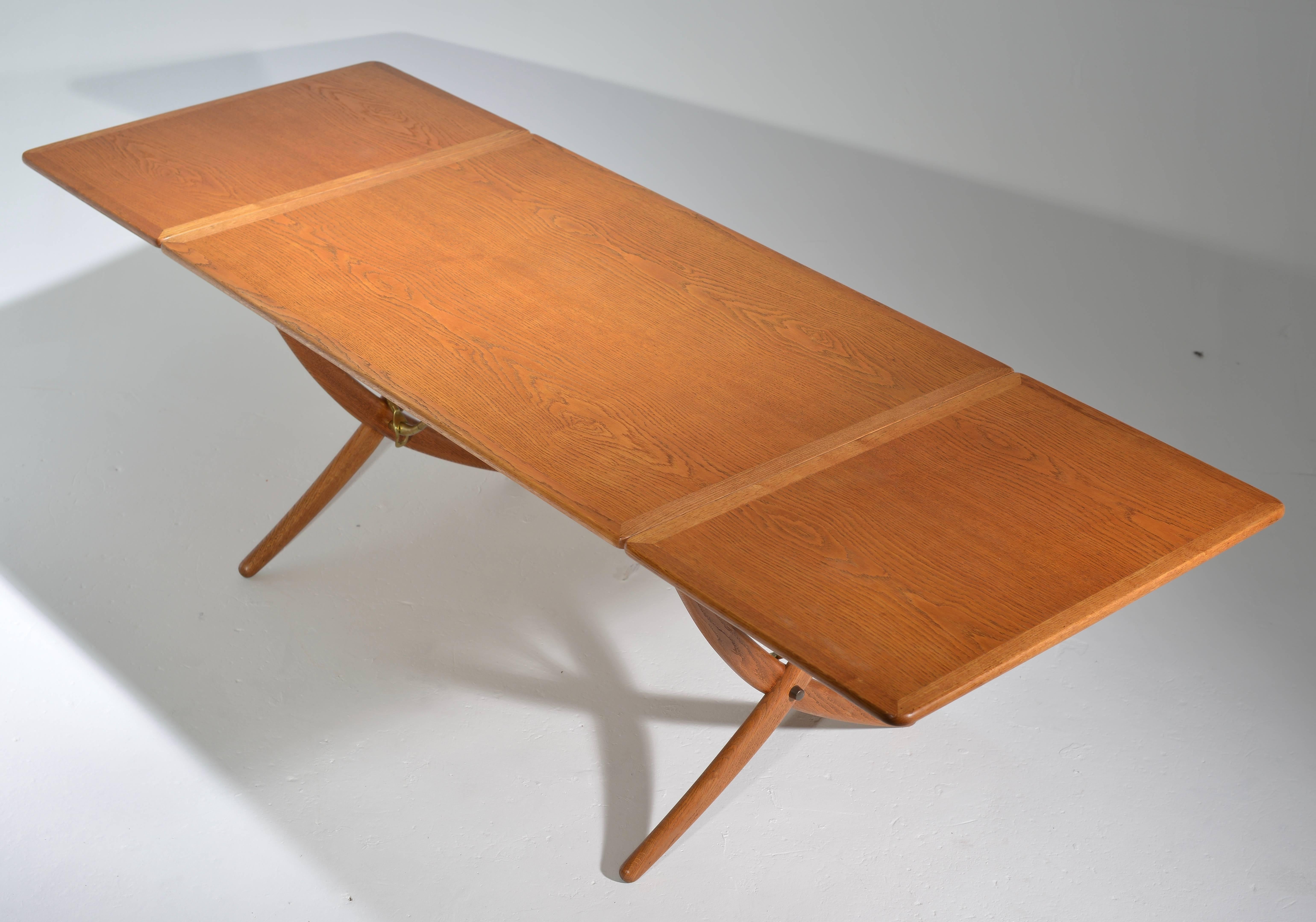 Il s'agit d'une table de salle à manger Hans J. Wegner AT-304, rare et ancienne, entièrement en chêne, avec deux abattants, des pieds croisés et des traverses en laiton.  Conçu par Wegner en 1950 et fabriqué par l'ébéniste Andreas Tuck, au Danemark.