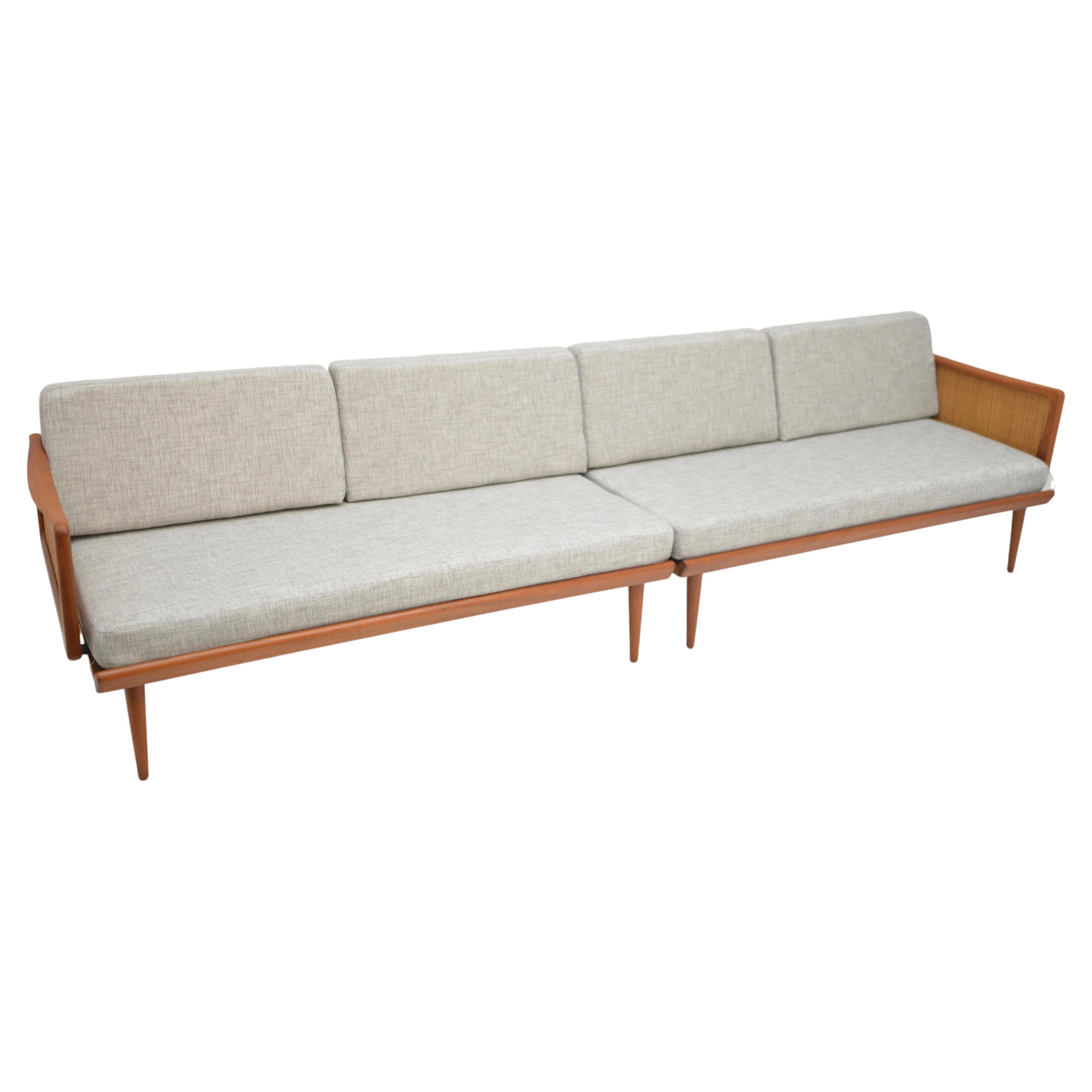 This multifunctional living room set can sleep two and provide all the seating you need. Both daybeds feature new upholstery and cushions, solid teak frames, and the arms have inset caned side panels that fold down to provide a longer resting space