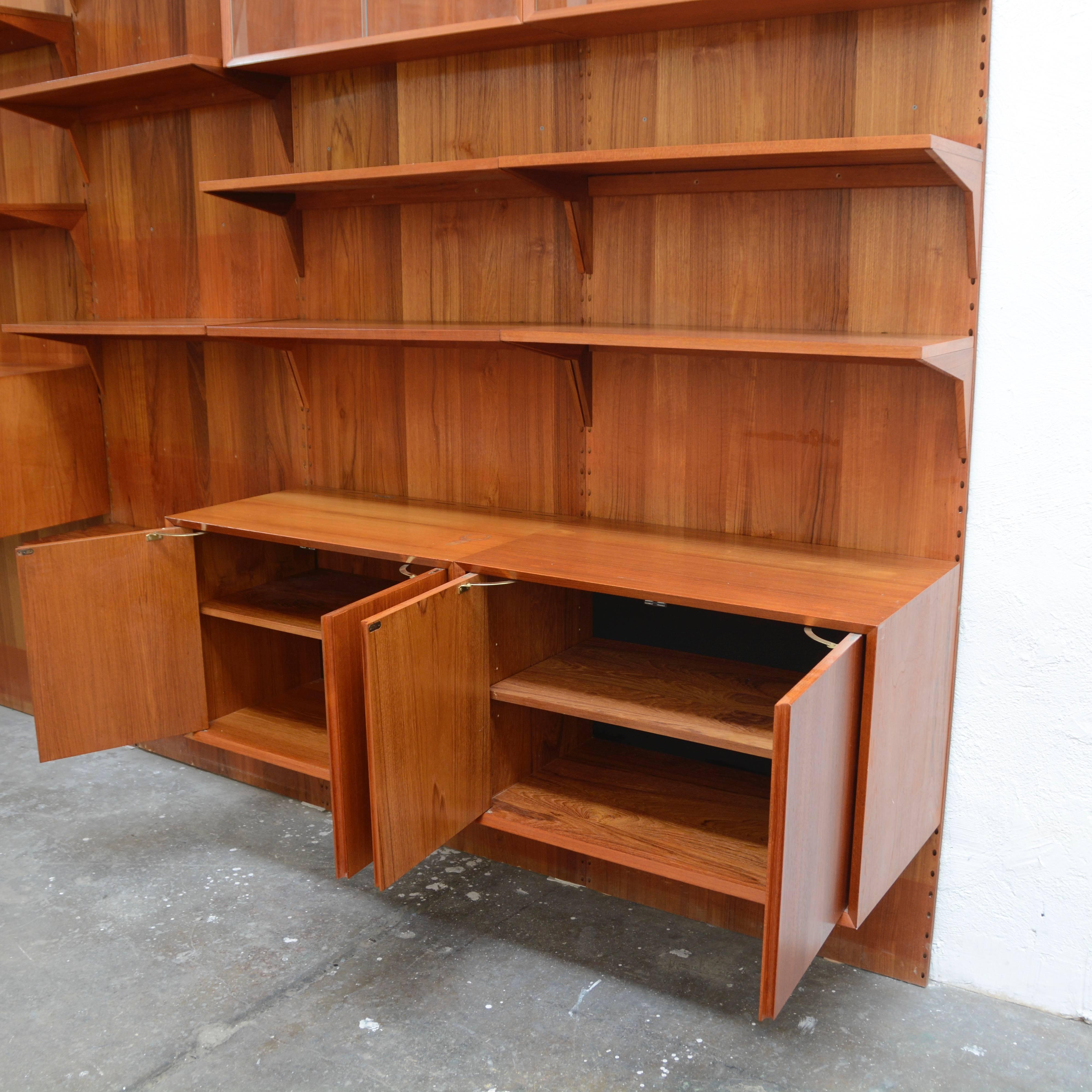 Highly versatile and functional wall unit in teak by Danish designer Poul Cadovius. 
The unit shown is an example of what we typically stock.  Units are sold by the component- wall rail, shelf, cabinet.  Please inquire for pricing and availability.  