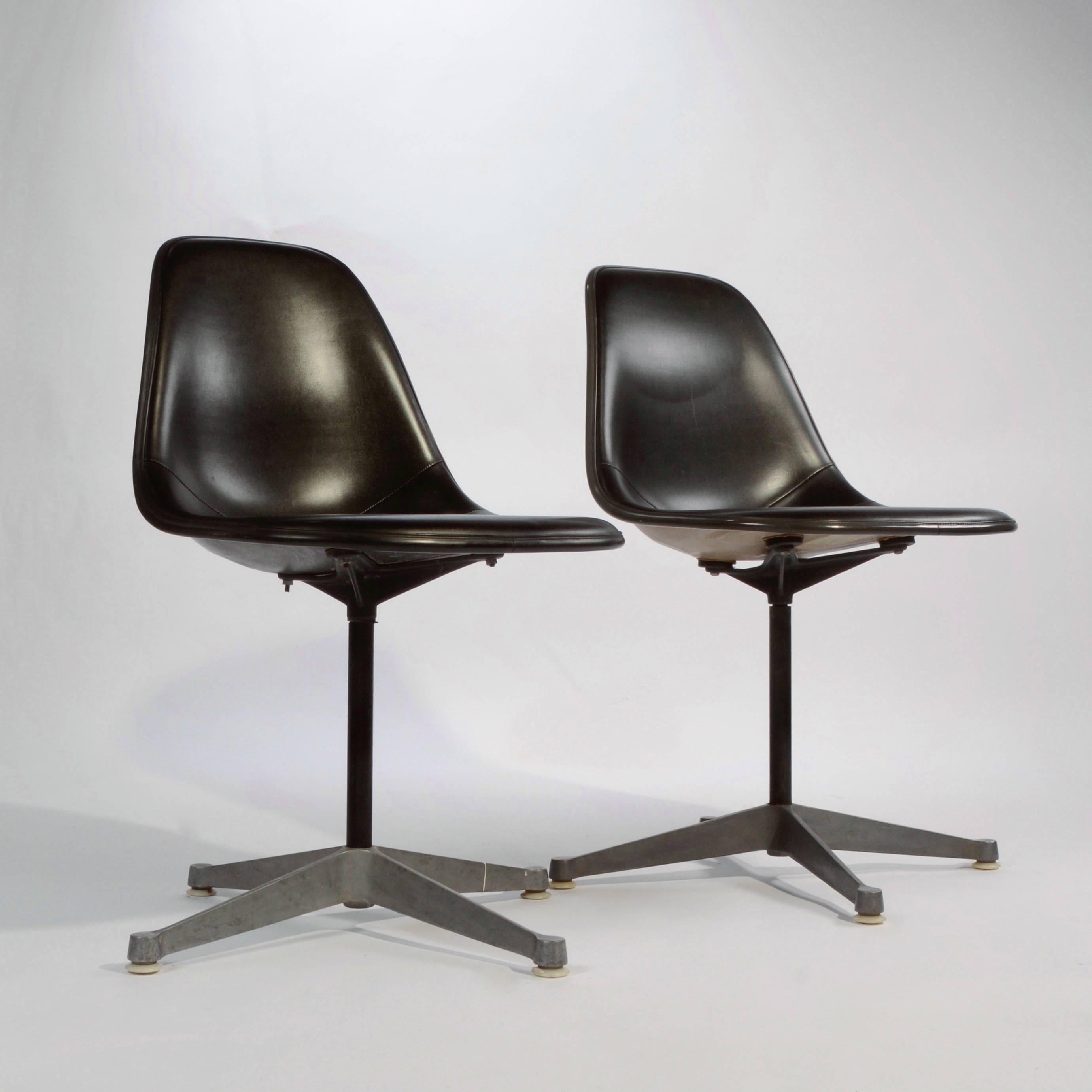 Pair of Herman Miller Eames chairs on aluminium contract swivel base. Shells are in good vintage condition and are upholstered in black vinyl.
