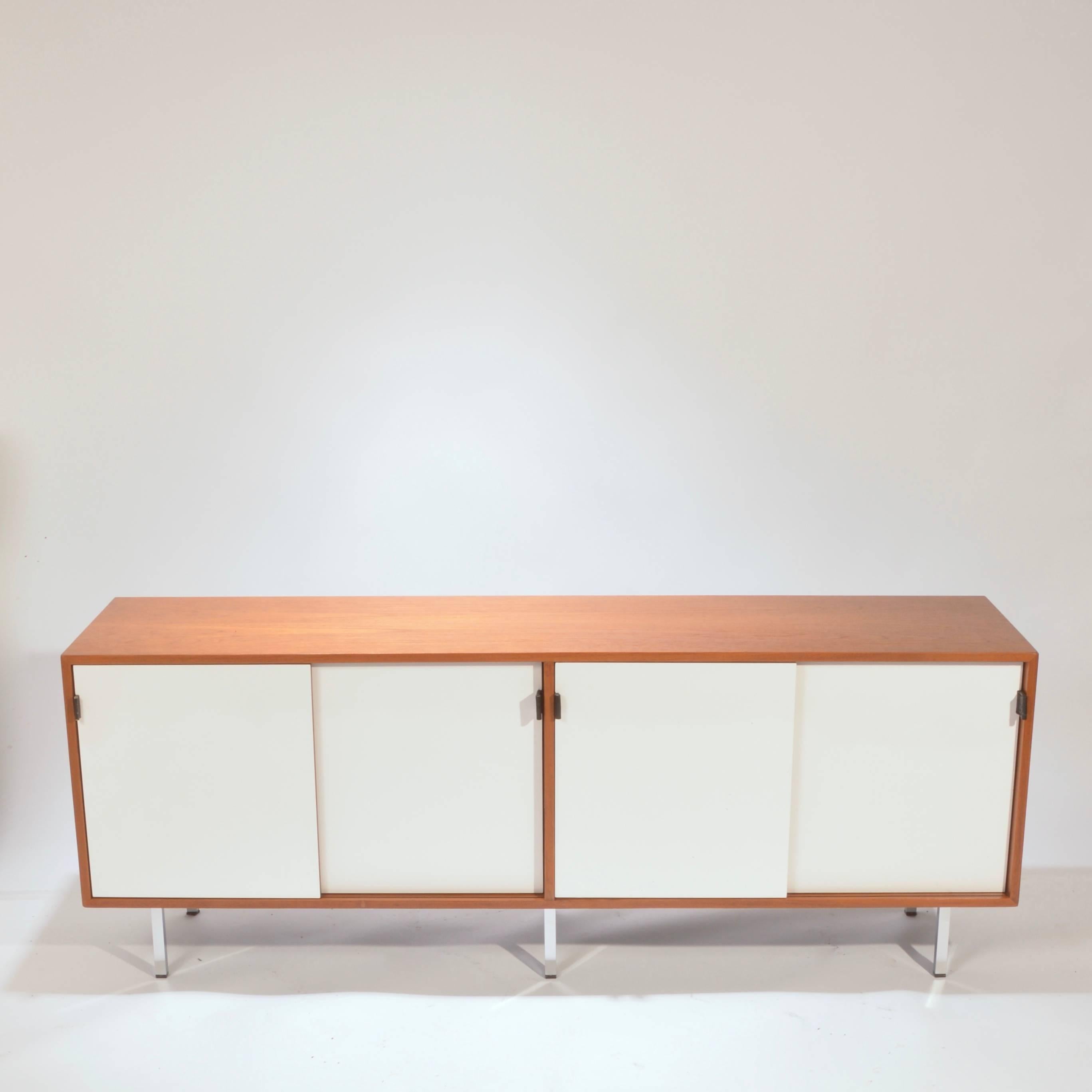This is a fully restored early Florence Knoll credenza featuring new white Formica sliding doors, new professional lacquer finish, leather pulls, chrome legs and solid oak drawers. We have six in stock and can offer a range of interior options such