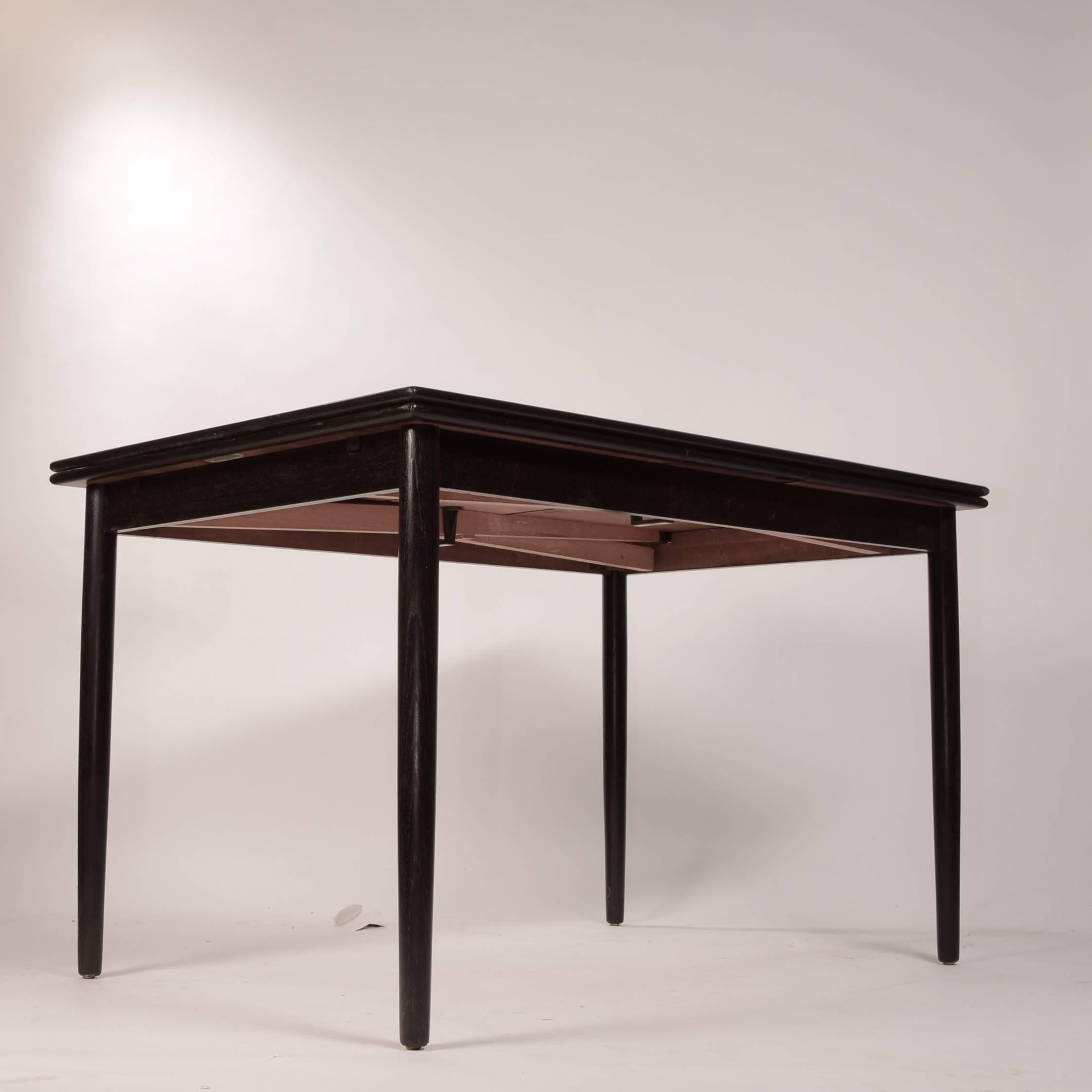 This is a great Danish modern draw-leaf dining table newly ebonized black. The leaves pull-out with easy. In excellent refinished condition. Measure: Total length with leaves pulled out is 84