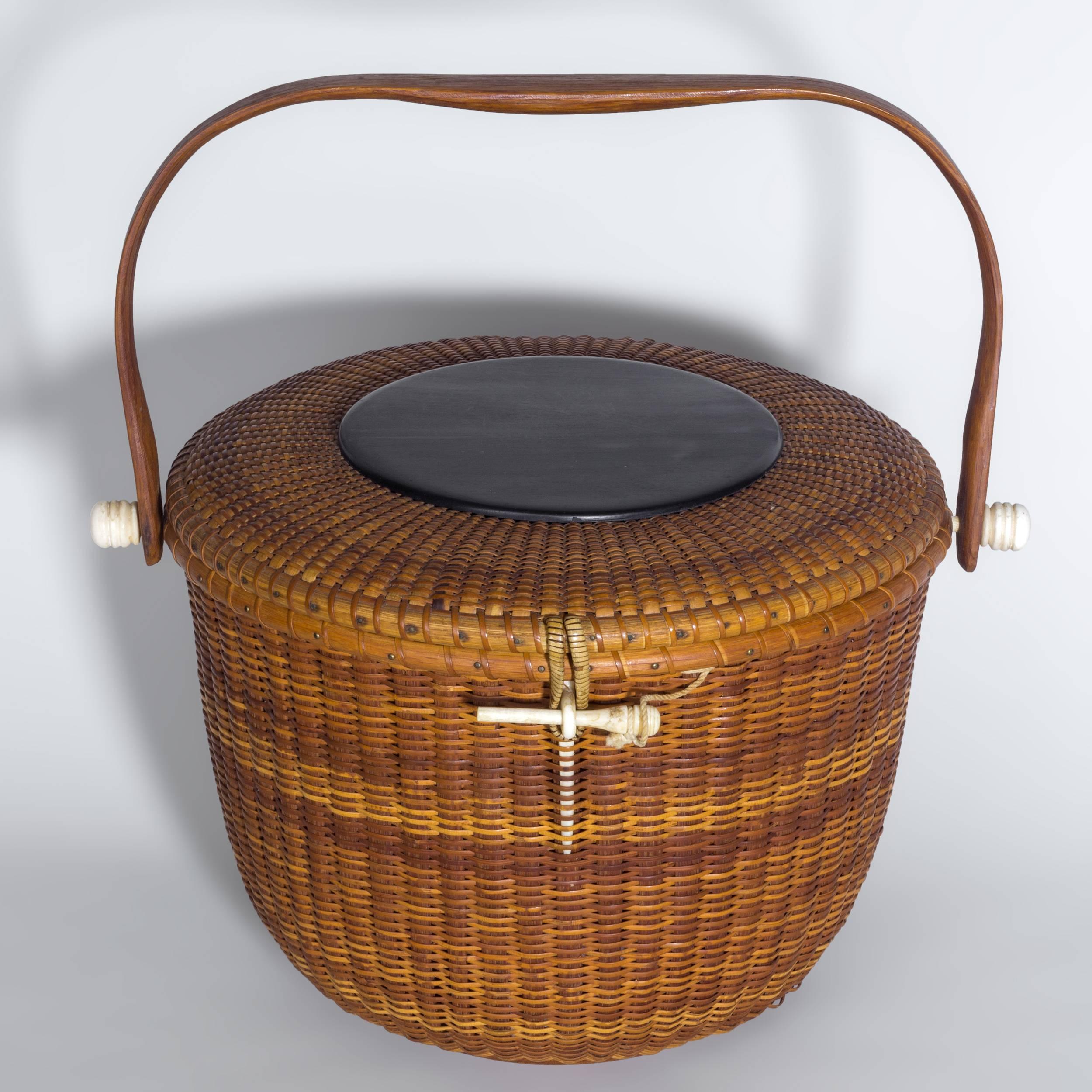 Rare large round form with sizable unembellished ebony top with great deep black color. Handle affixed to rattan-woven body by boldly turned knobs, with carved eye and turned peg for closure. Exterior base clearly inscribed 