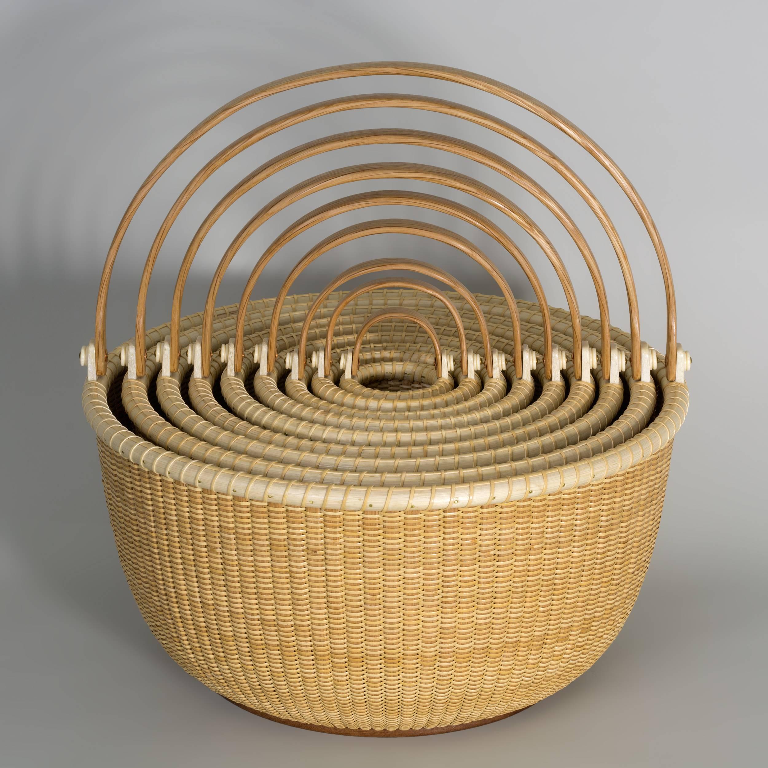 Classic nest of nine baskets by highly collected contemporary Nantucket artists Bill and Judy Sayle, who have been producing these works of art for over 40 years.  Each basket is meticulously crafted with carved and bent swing handles, bone ears,