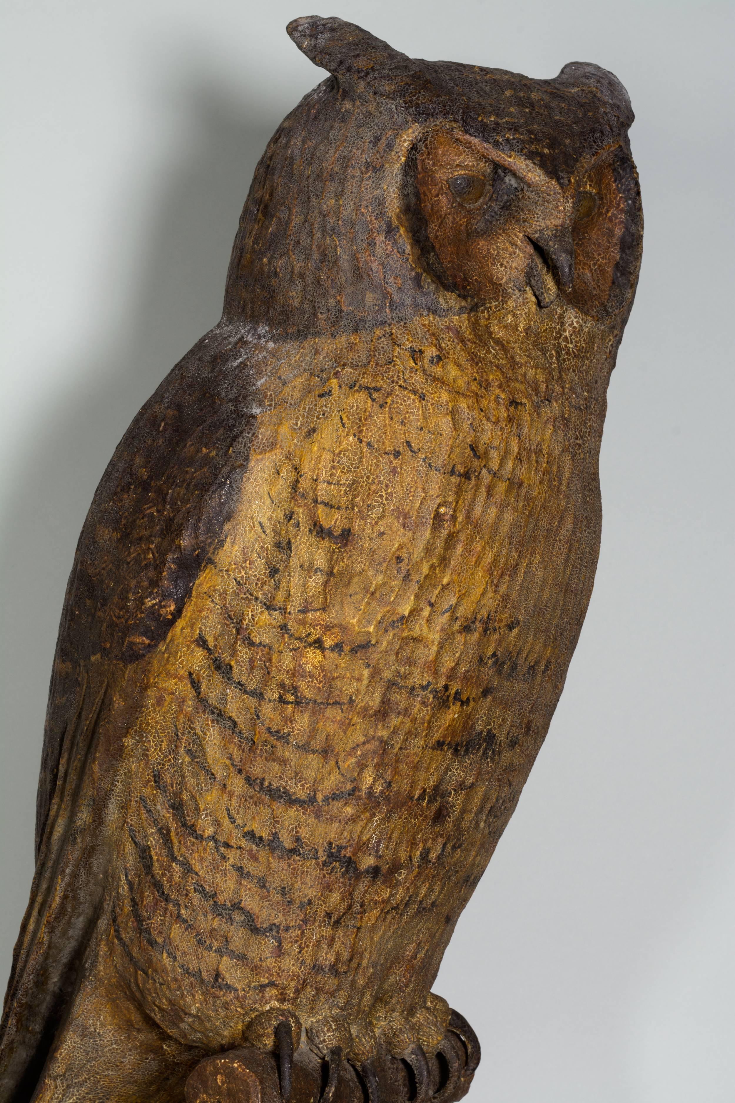 An outstanding carved & painted life size great horned owl carved by noted artist Frank Finney, b.1947. Hollow-carved out of Tupelo wood with realistic antique looking paint and is mounted on a perch with the beak partially opened. A fine example of