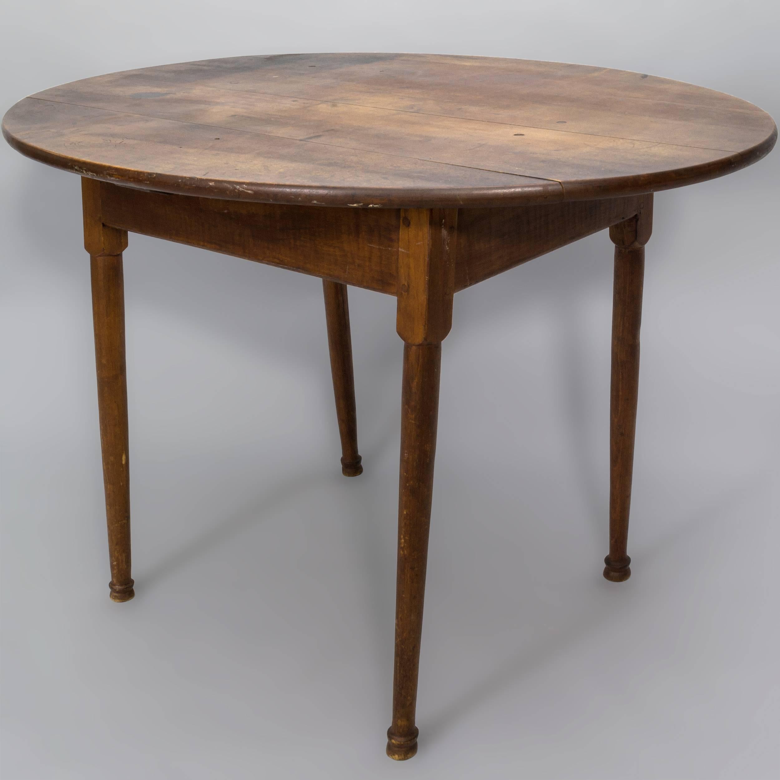 Oval tea table with overhanging two board pegged 
Cherry top on rectangular base with Tiger Maple 
skirt with molded edge with the cleat carved through 
it.The legs are block turned and tapered, ending on ringed
button feet. Rhode Island,