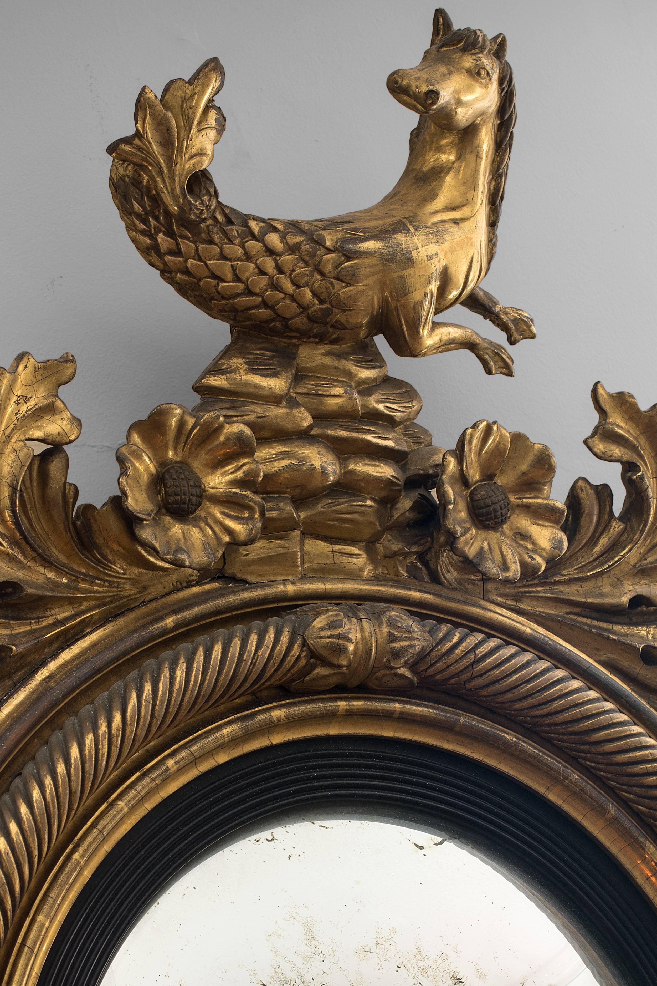 Important Regency carved gilt wood girandole mirror. The 
convex mirror plate within an ebonized reeded surround and 
rope twist molded frame. A hippocampus sits above acanthus 
leaves and sunflowers, the bottom having more acanthus 
leaves and