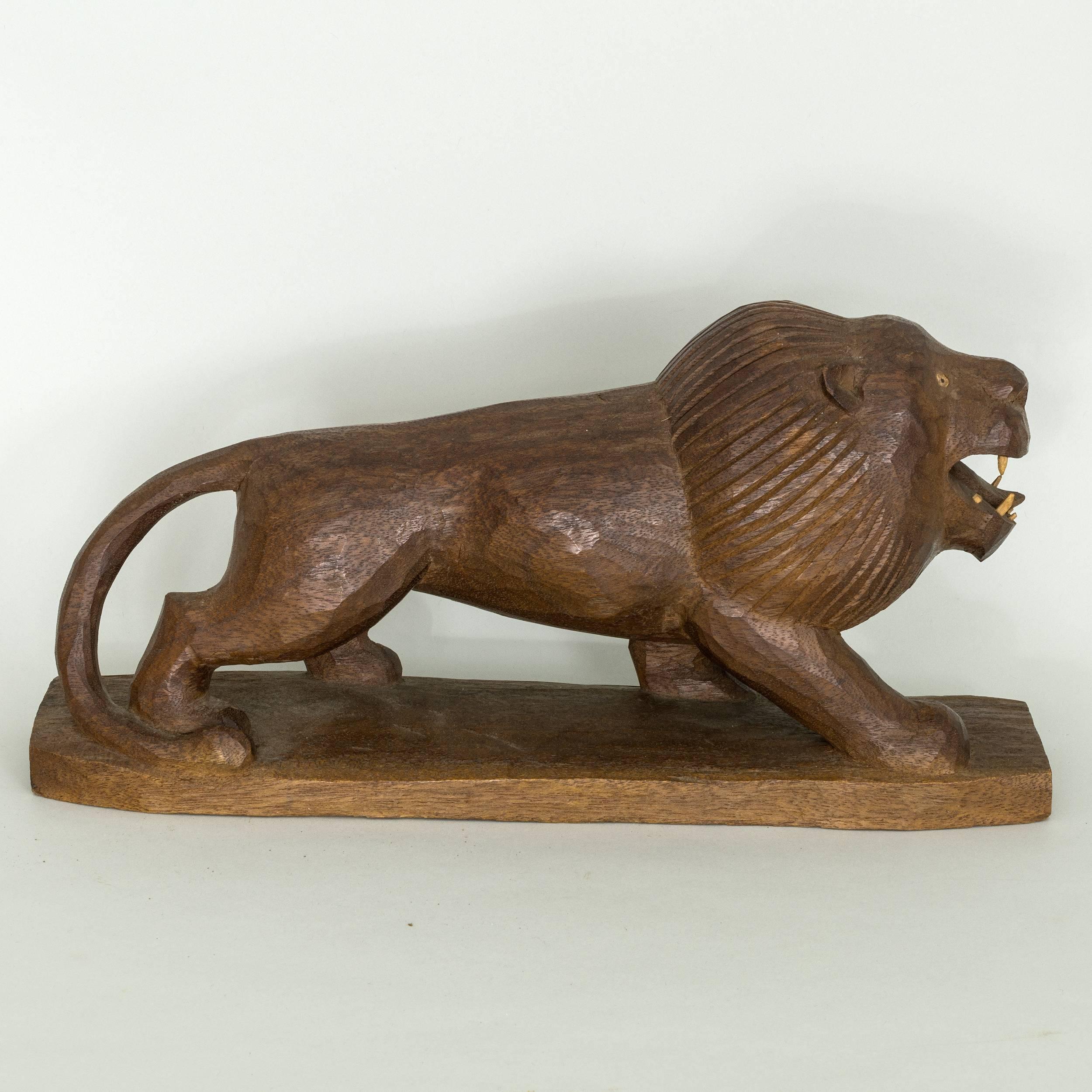 Carved primitive crouching lion on base with black 
eyes and carved teeth, American, c.1930-1940
						