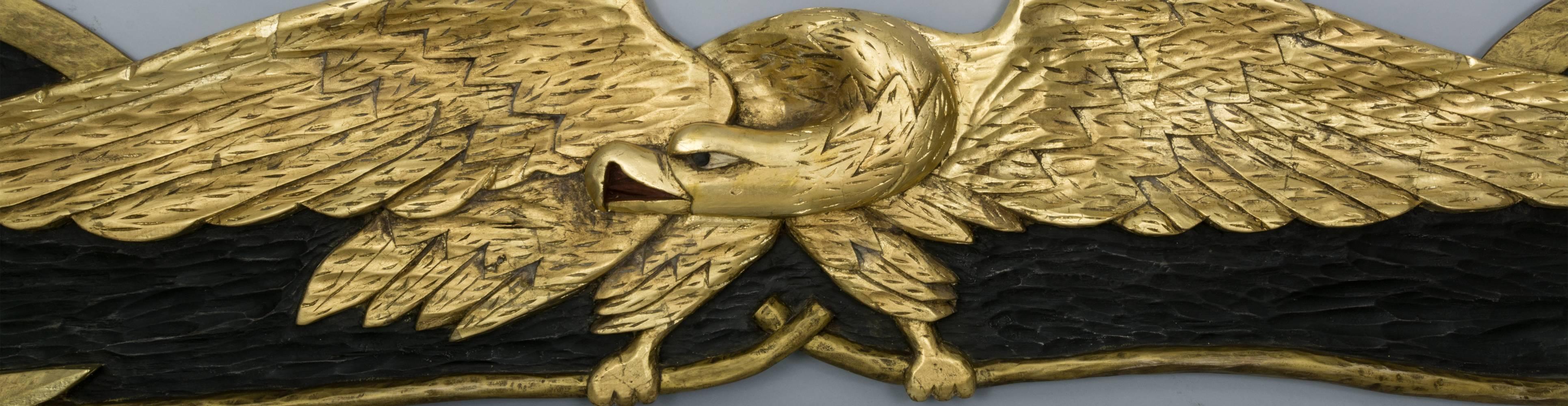 Large stern board eagle plaque depicting a displayed.
Eagle clutching arrows in its talons with a scrolled
backboard. Carved from a single piece of pine with
gold leaf and black painted ground. Signed on the back
“Dick Steele Rockport