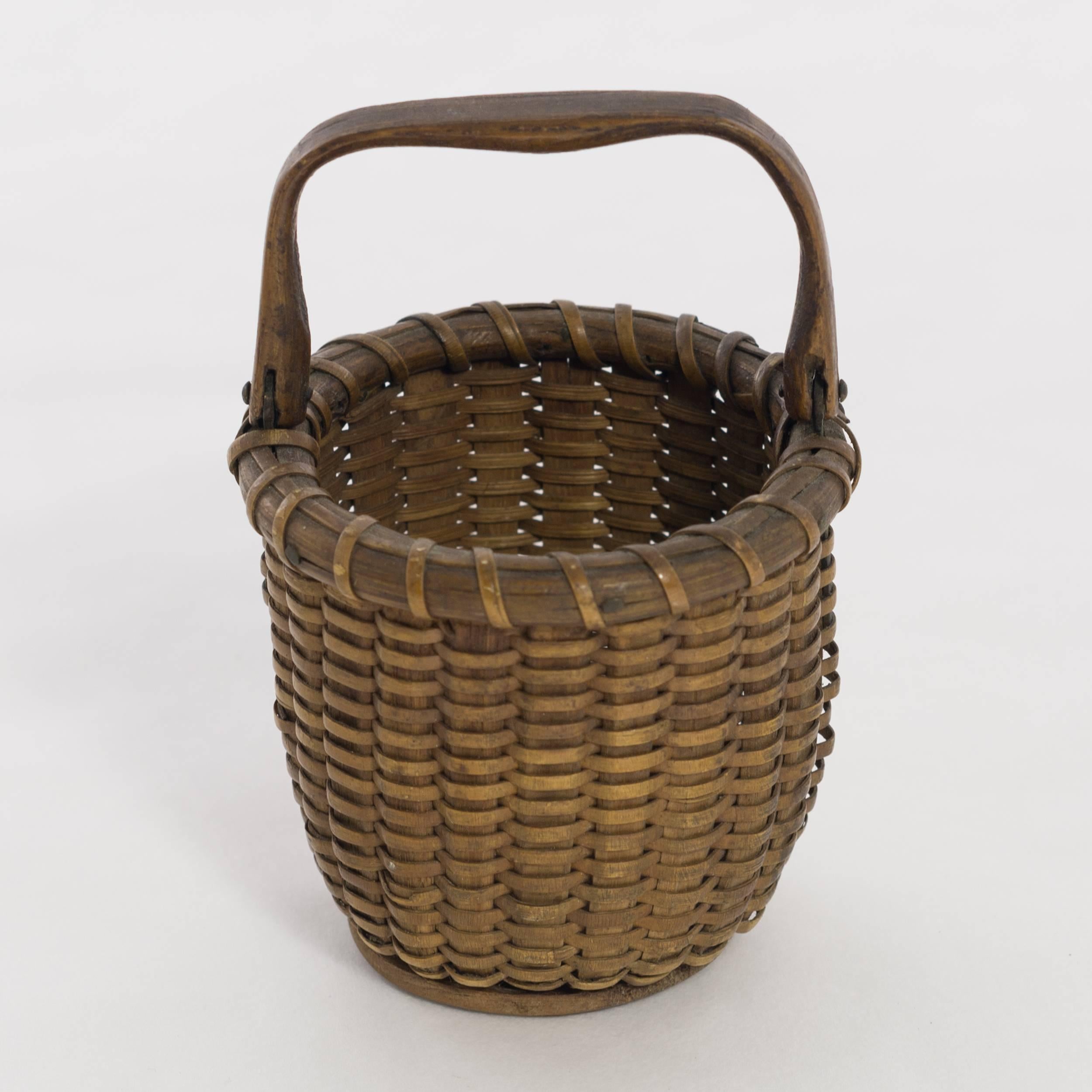 Miniature Nantucket lightship basket, made with oak staves and swing handle,
with a maple base. Attributed to Clinton Mitchell Ray, circa 1930.